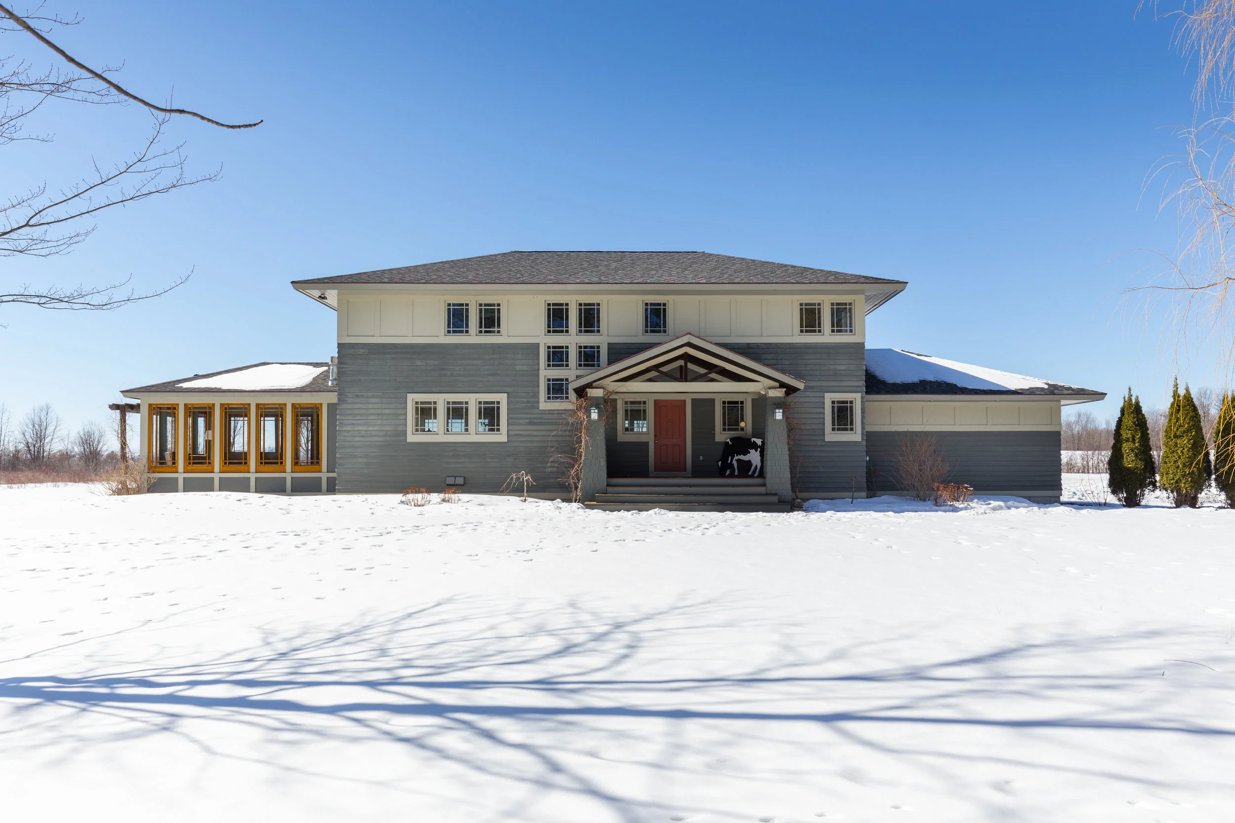 This new four-bedroom house is based on an earlier design for the same client. He liked the first version so much, that when he built this second house, he asked LA to reduce the size and enhance it with Prairie style details. The horizontal window band on the exterior mirrors the long hip roof that has wide overhangs. The entry porch columns and gable roof add to the Prairie characteristics. The house is balanced by a garage on one end and a glass enclosed family room on the other. A custom designed stair and railing provide more architectural style. The kitchen, with large cooking island and cherry cabinets, overlooks the dining and living rooms, two steps down. A bookshelf flanked fireplace area provides a cozy reading niche.