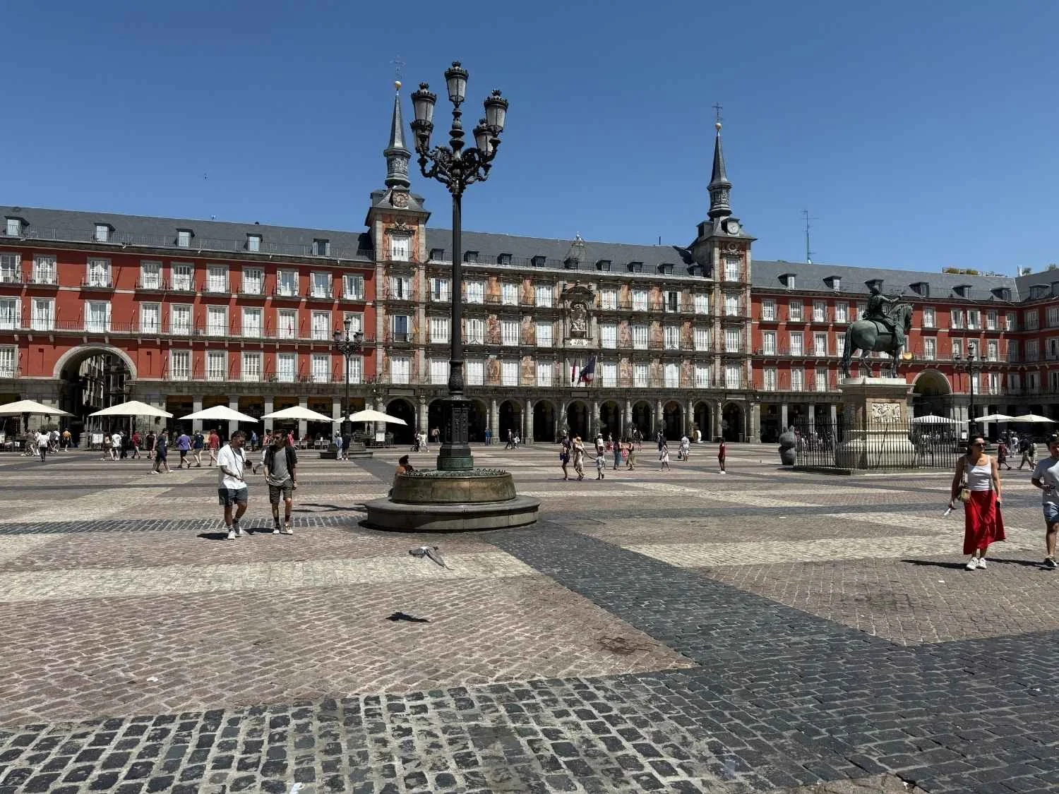 People walk through Plaza Mayor, Madrid's iconic central plaza and a must-visit stop on any visit to Madrid with kids.