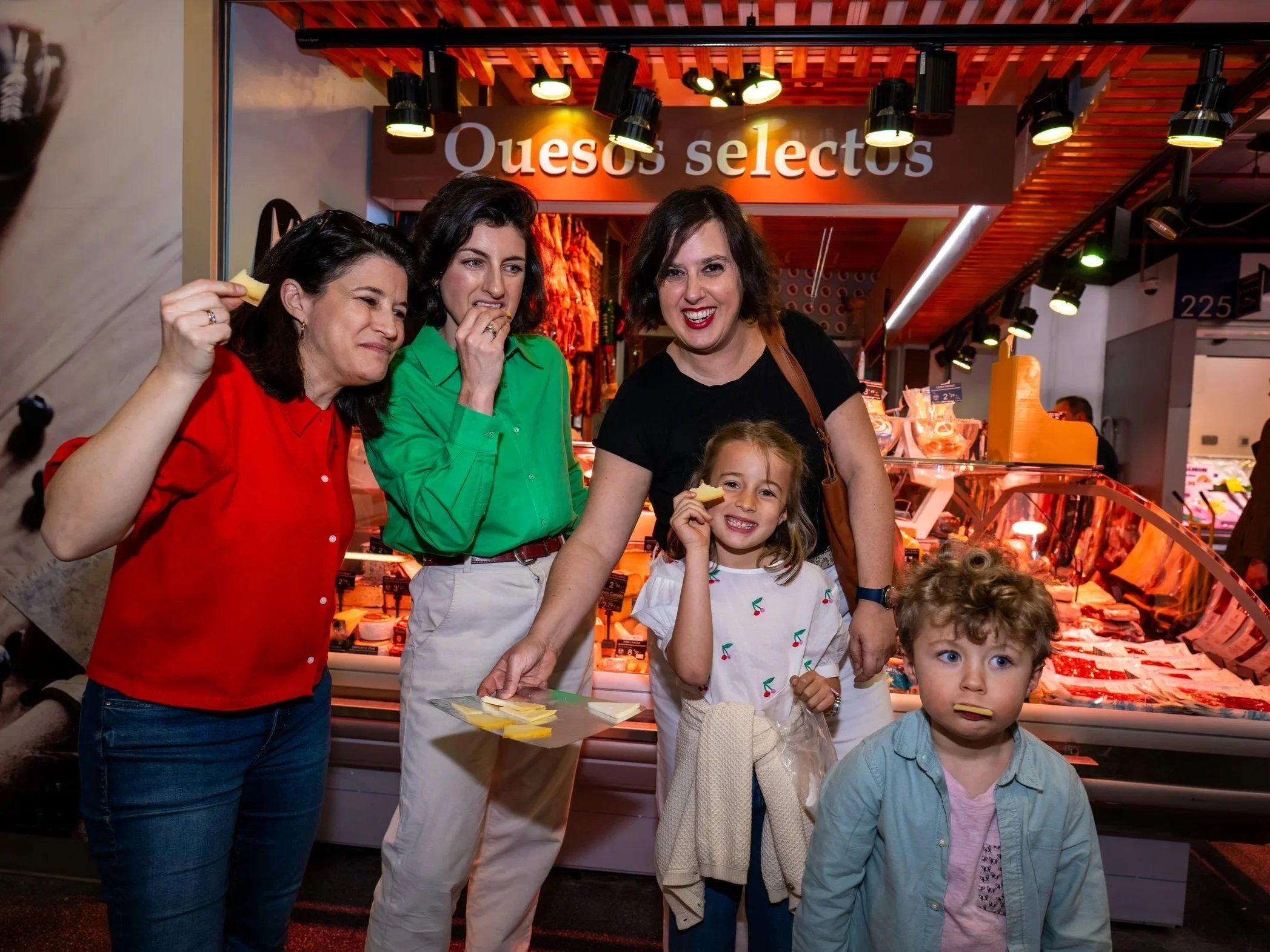 A family enjoys a cheese tasting in a traditional market in Madrid during a food tour for kids.