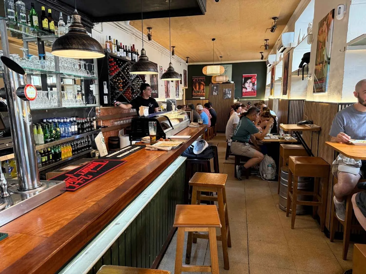 Diners enjoy tapas at low tables and along the bar at Taberna El Sur, a great family-friendly tapas bar in Madrid.