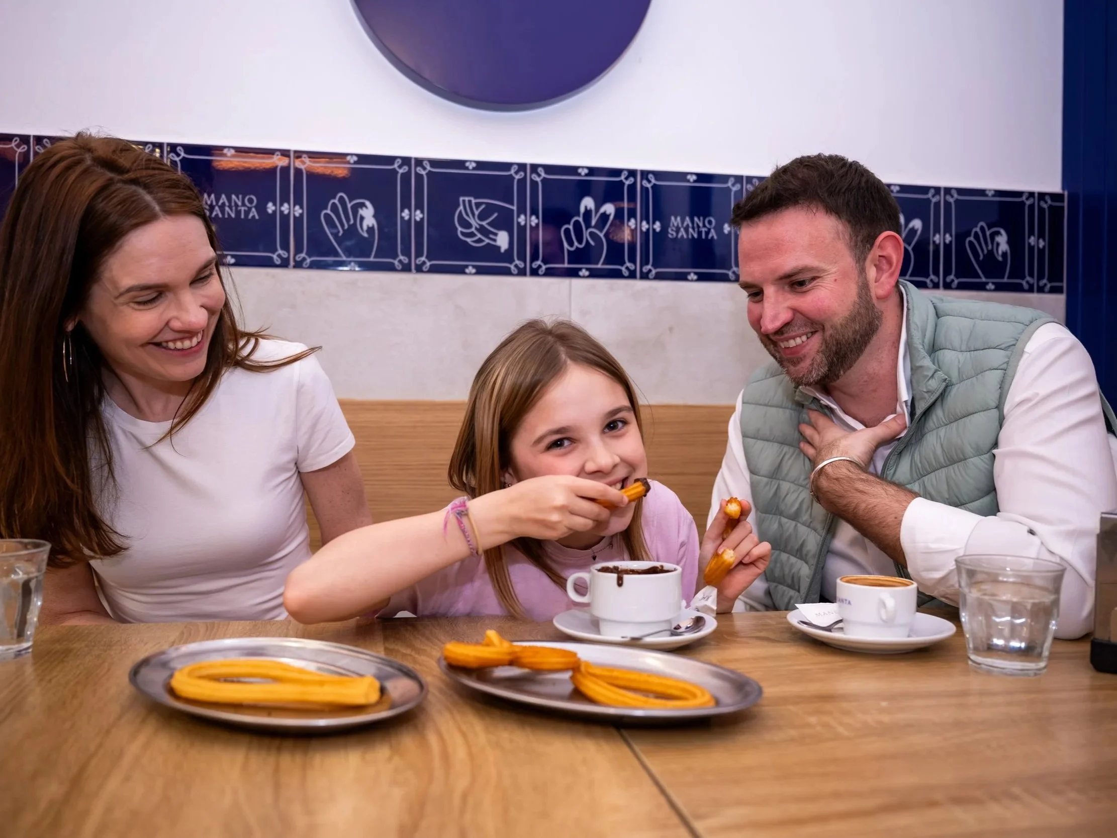 A family enjoy freshly made churros and hot chocolate on Walk and Eat's family food tour in Madrid.