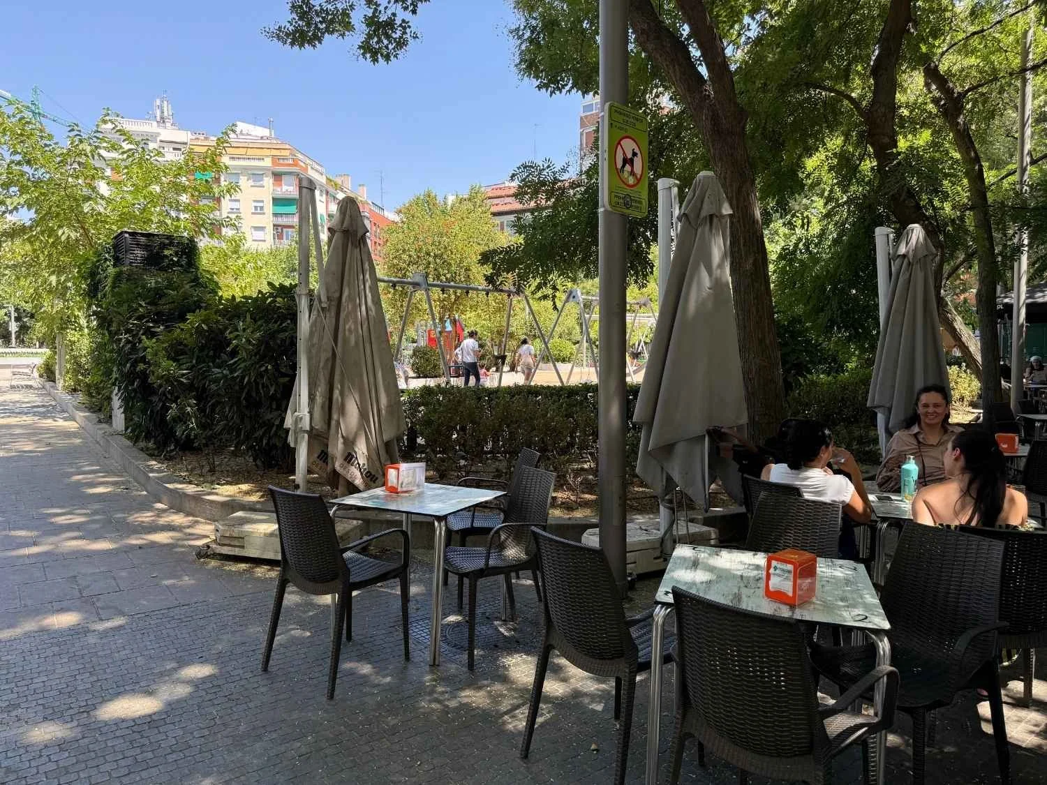 Outdoor tables overlook a playground in Plaza Olavide, one of the best plazas to visit in Madrid with kids.