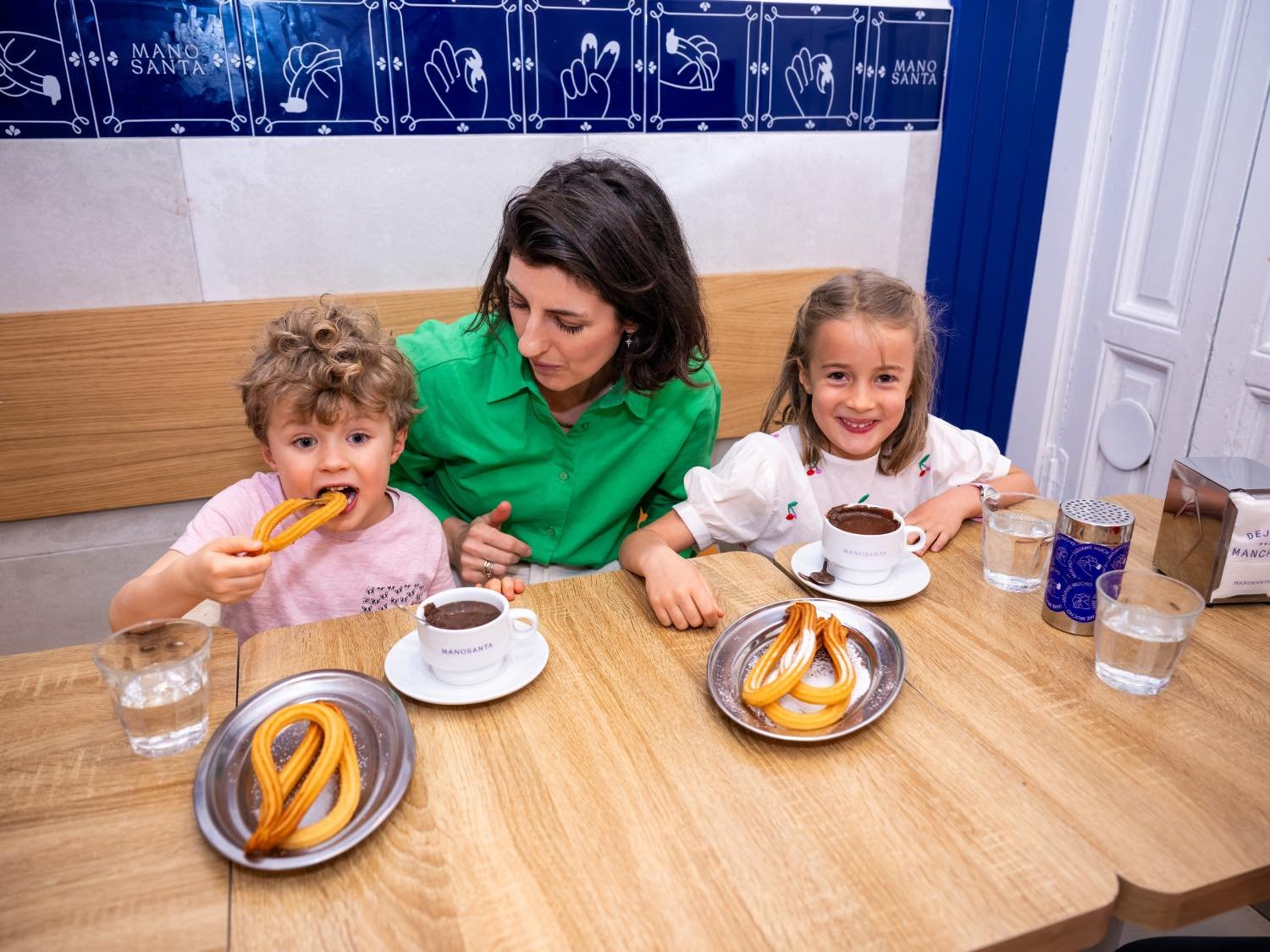 A mom and her two young kids enjoy churros and chocolate on a family-friendly food tour in Madrid over the Christmas holidays.