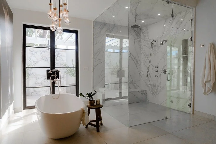 Natural light floods the space, highlighting the book-matched marble, warm wood tones, and sculptural lighting. Every element was chosen to create balance — clean lines, soft neutrals, and thoughtful details that bring a spa-like calm home.
A