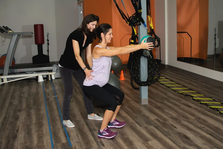 A therapist guiding a patient through a squat