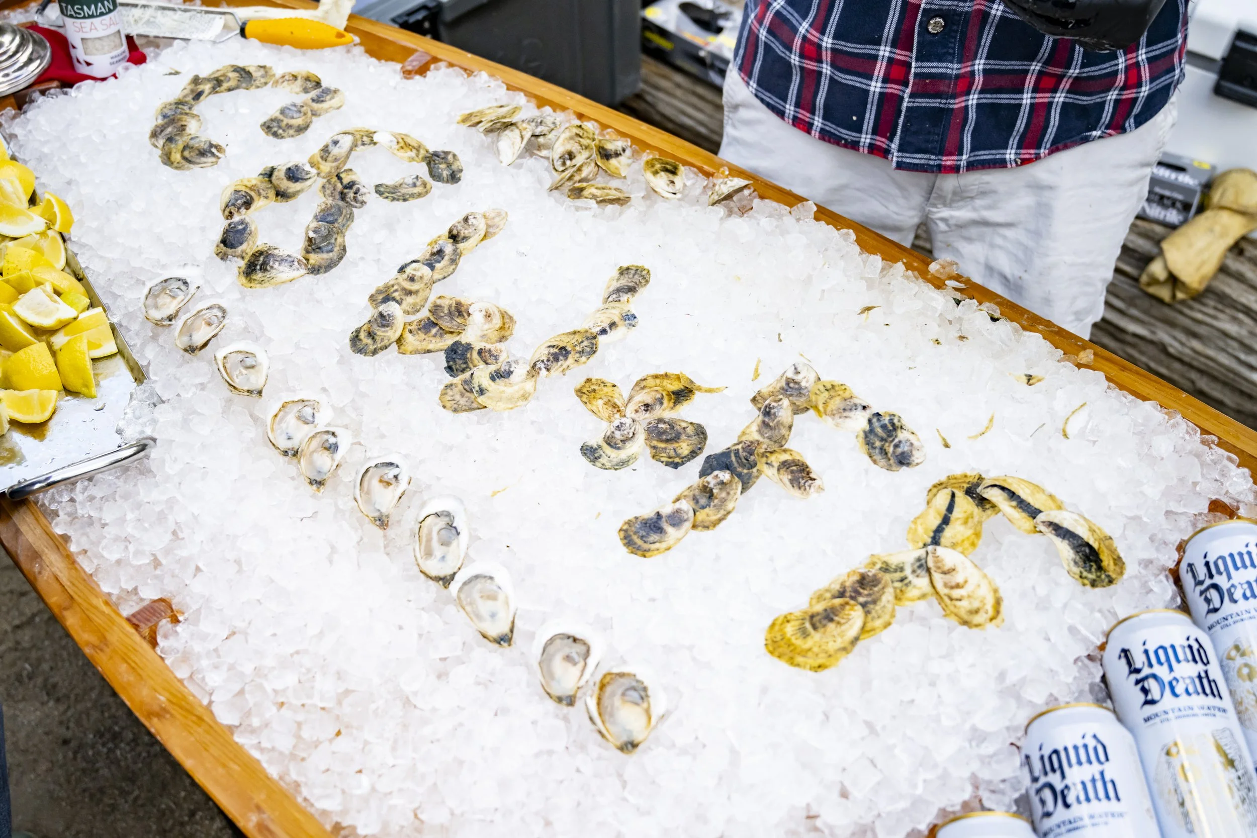Display of oysters on crushed ice with the word "LOVE" spelled out using the oysters. Lemon wedges are visible on the side.