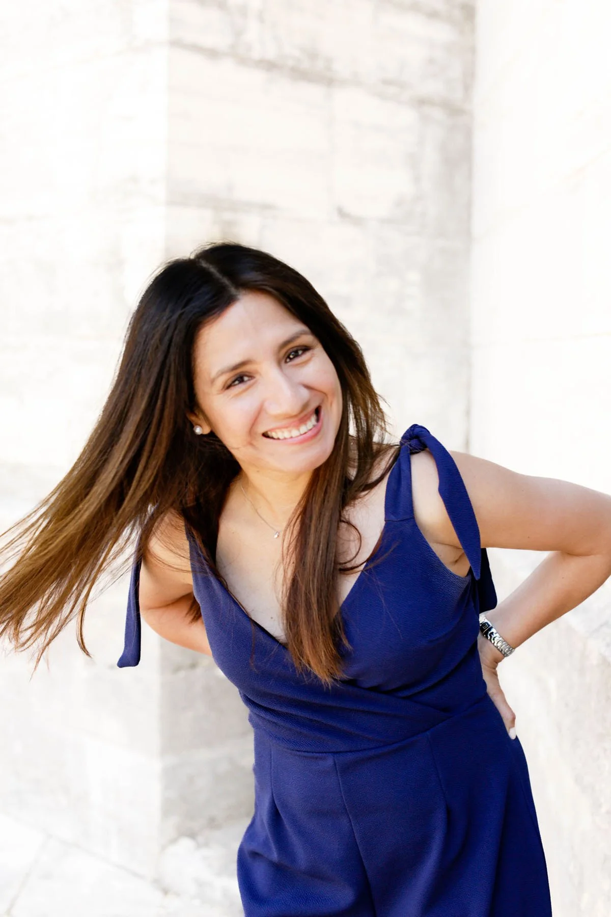 Lucía with a big smile, standing outdoors against a yellowish stone wall.
