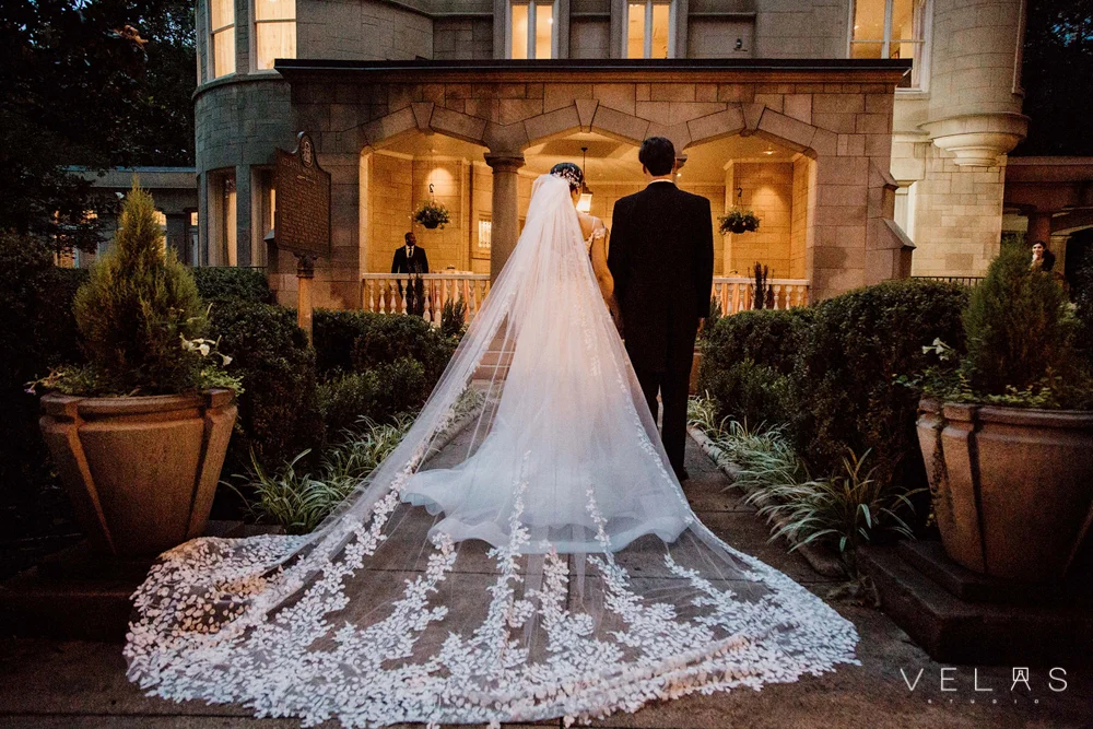 Bride with cathedral veil and groom in front of The Wimbish House.