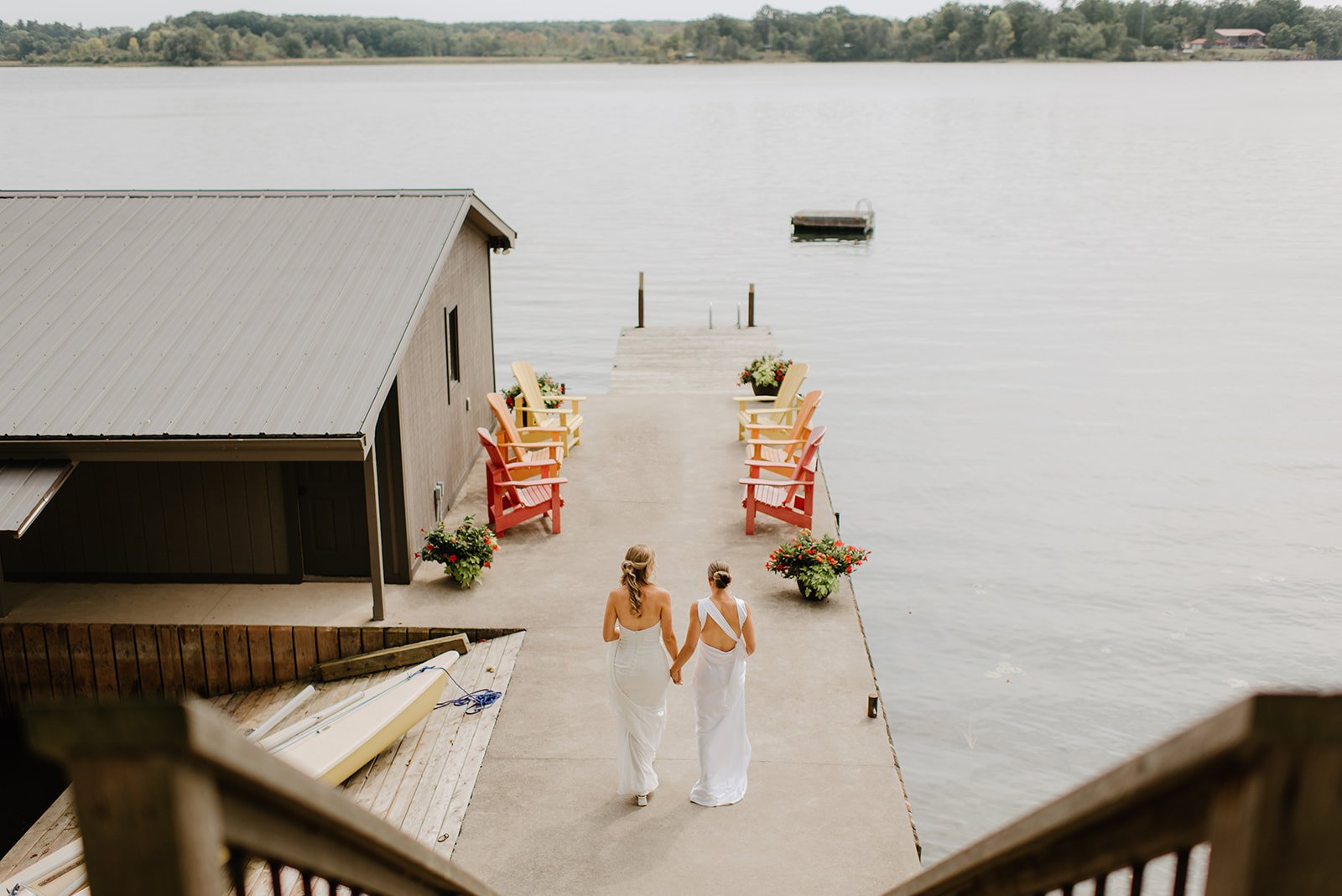 Family Home Kingston Wedding of Vanessa and Liz – two brides walking hand in hand down a path toward the lake, surrounded by nature