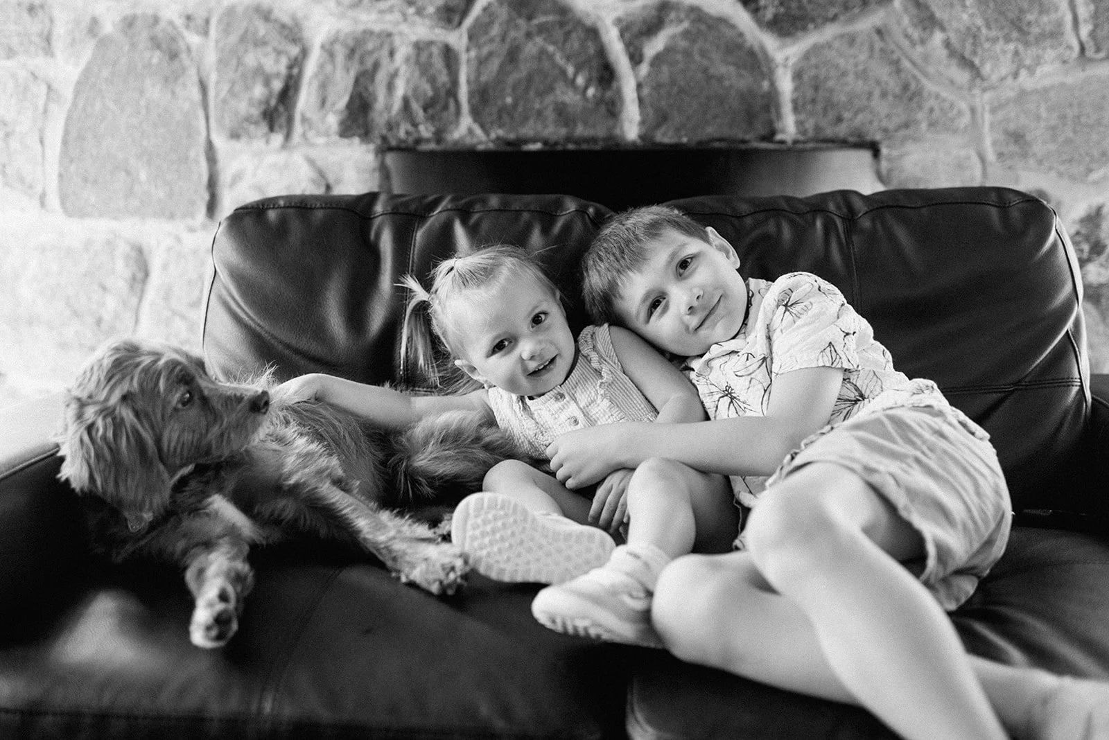 Eaton Hall Wedding in King City | Benita + Allen – A black and white portrait of two children cuddling on a couch with the family dog during the wedding day.
