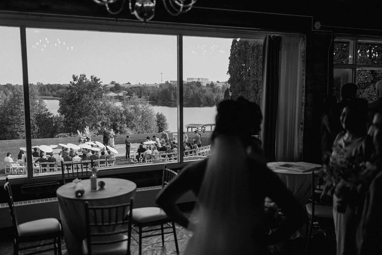 Eaton Hall Wedding in King City | Benita + Allen – Outdoor ceremony setup with white chairs and floral arrangements by the water.
