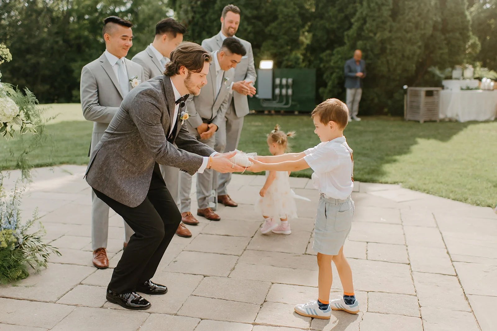 Eaton Hall Wedding in King City | Benita + Allen – The groom shares an emotional moment with the ringbearer during the outdoor wedding ceremony at Eaton Hall.