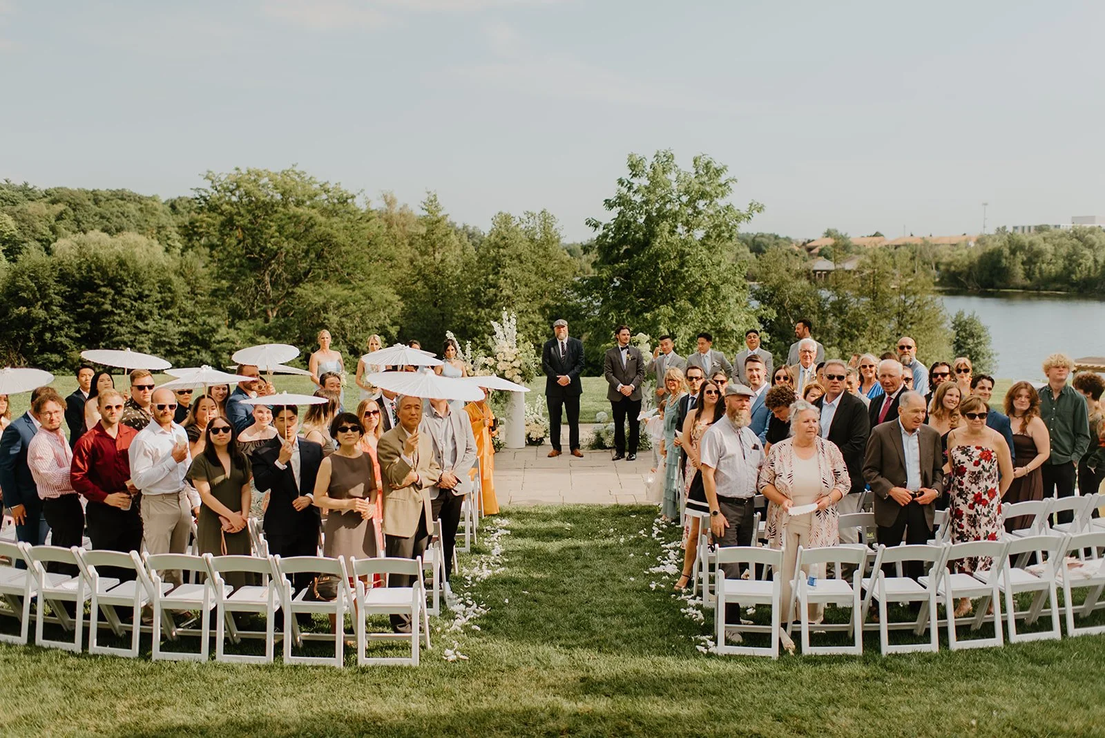 Eaton Hall Wedding in King City | Benita + Allen – Wedding guests holding chic white umbrellas to stay cool in the sun.