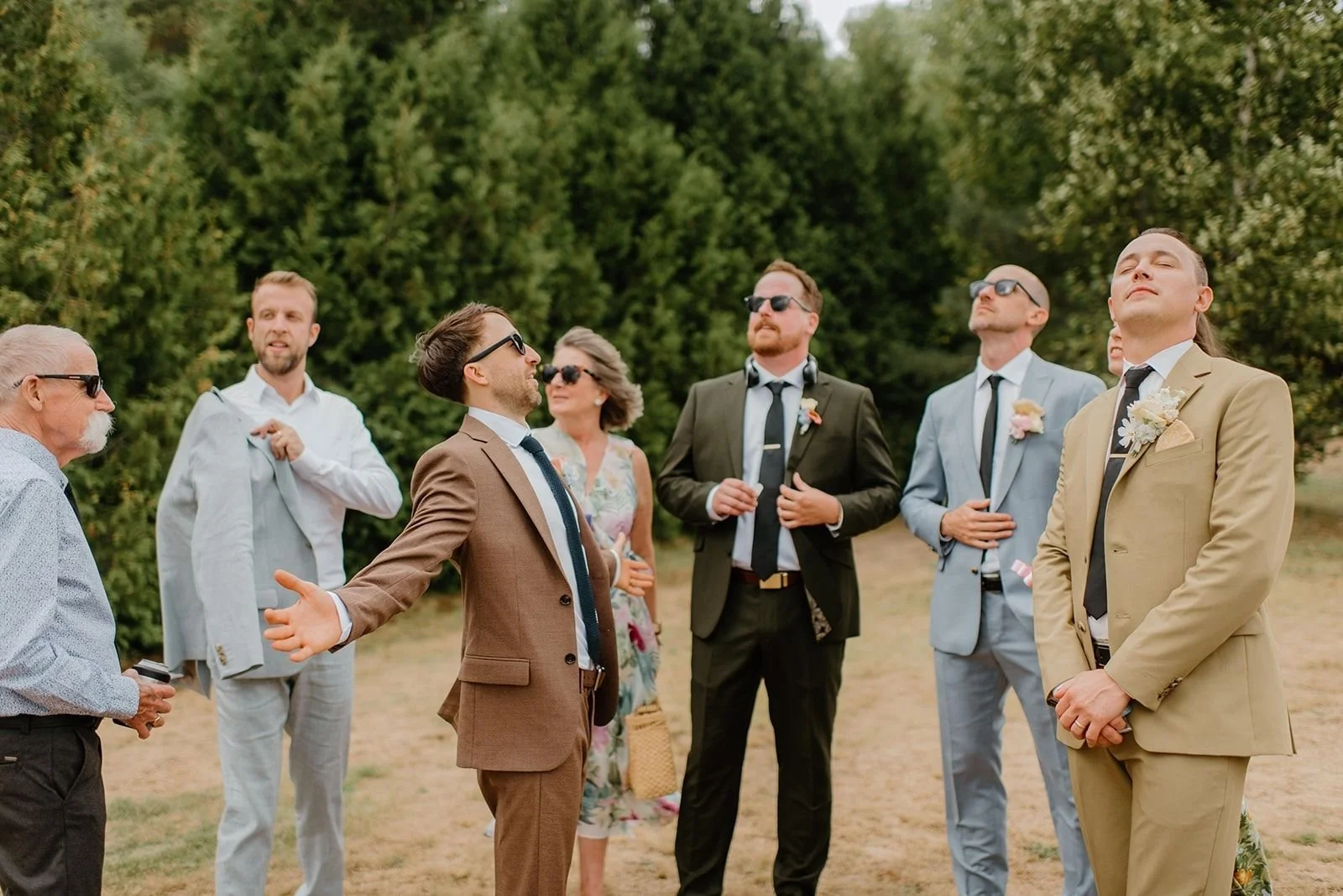 Camp Eden Woods Wedding in Ontario | Amy + Rory – The groom and his groomsmen in various stylish suits relaxing outdoors before the ceremony, showing casual cottage country wedding vibes.
