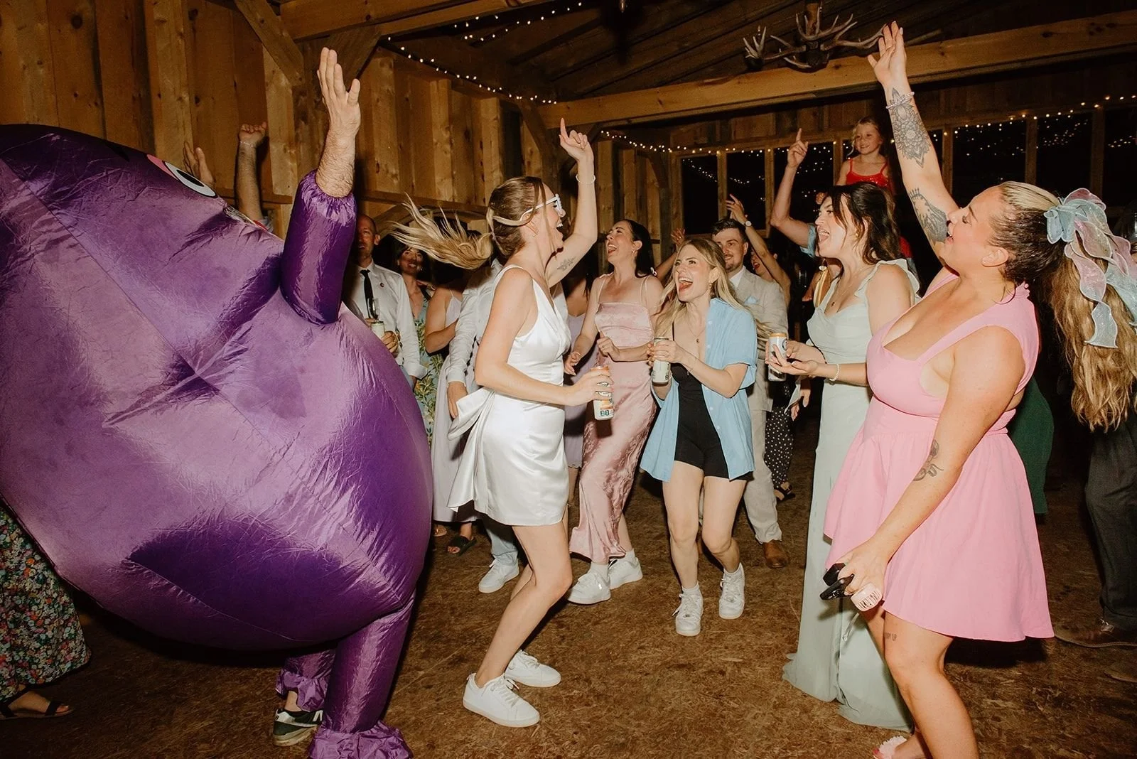 Camp Eden Woods Wedding in Ontario | Amy + Rory – High-energy scene on the indoor dance floor with a guest in a vibrant purple inflatable suit.