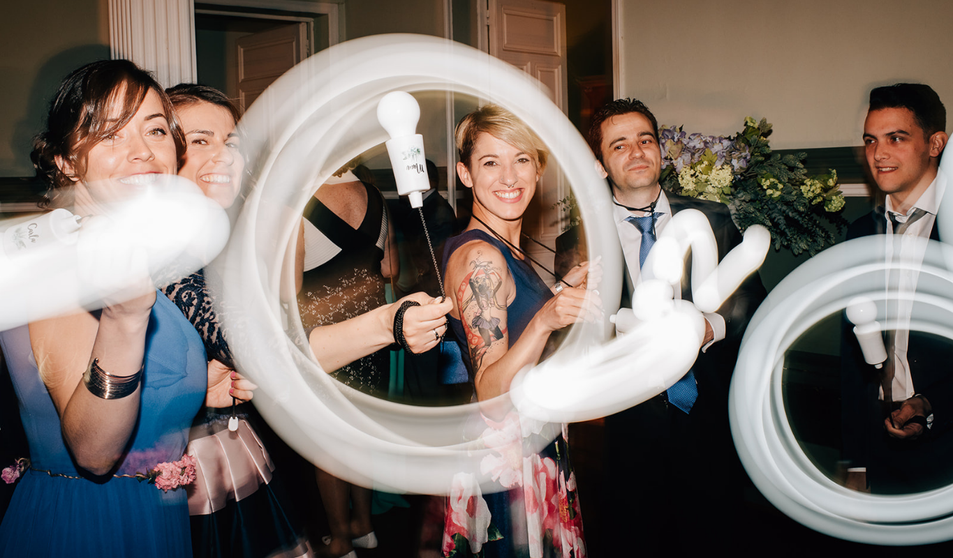 Guests waving glow sticks and portable bulbs on the dance floor at a wedding reception.