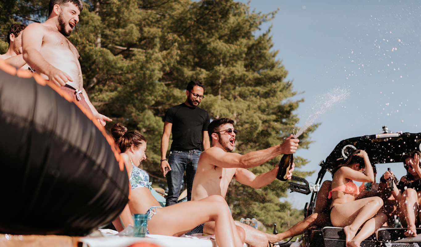 Guests jumping into a lake, laughing and having fun.