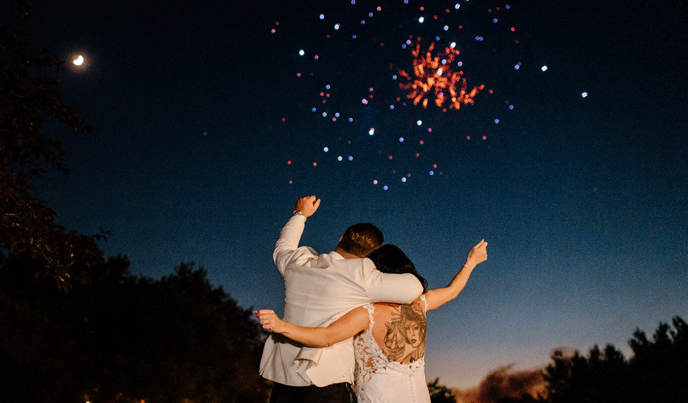 Couple watching a colorful fireworks display at a wedding reception.