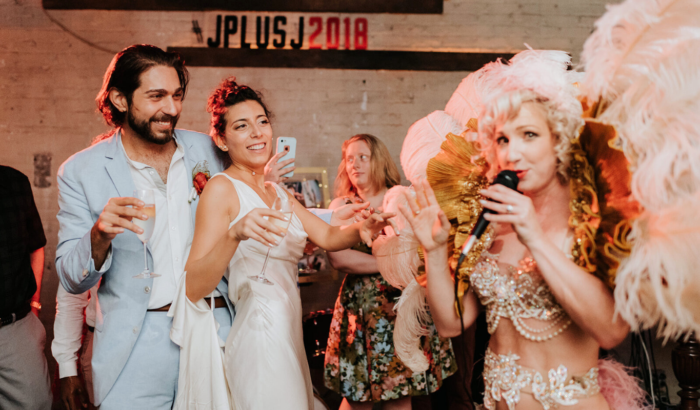 A burlesque dancer performing a playful routine at a wedding reception.