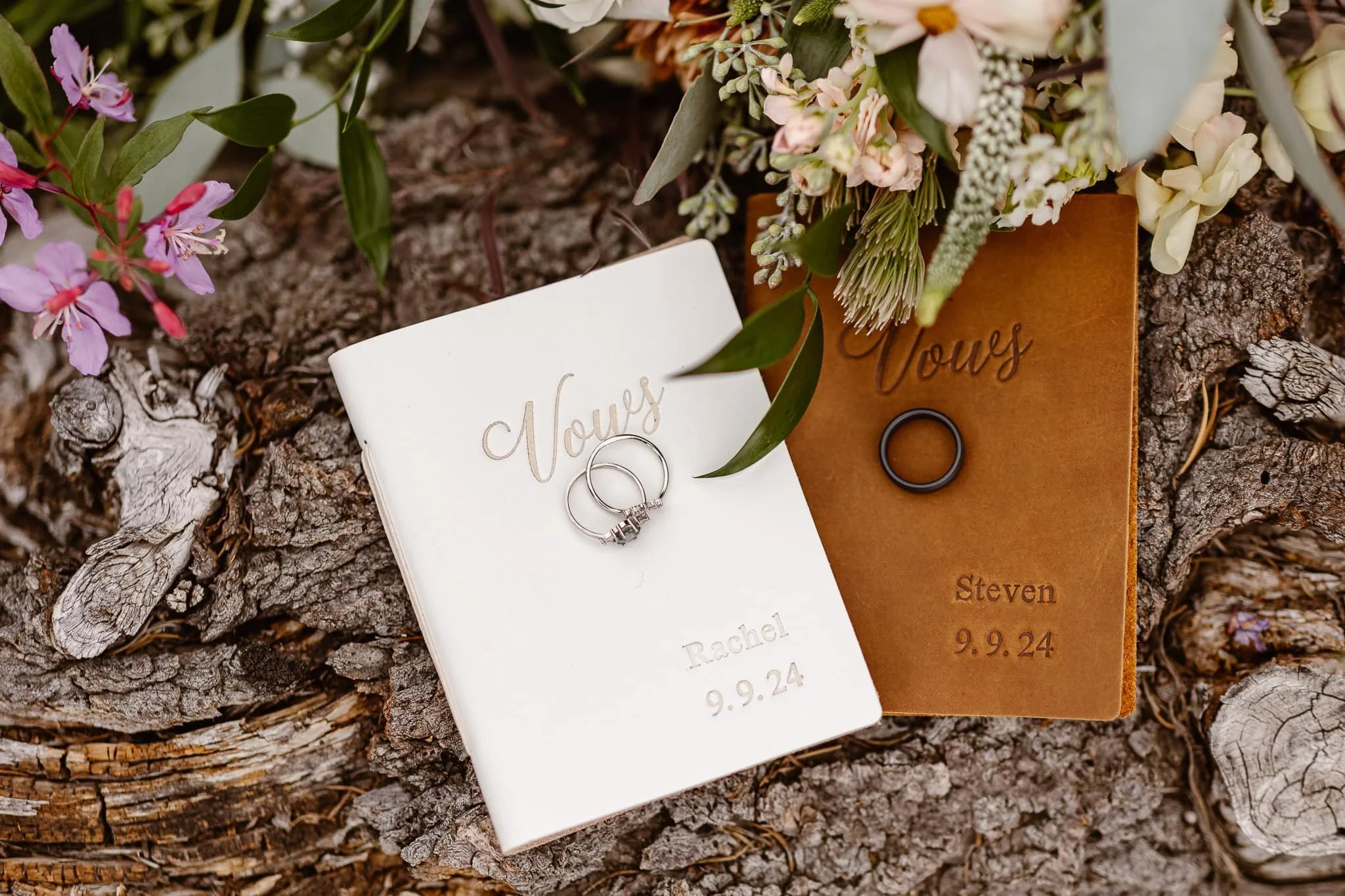 The bride and groom's custom leather vow books with their names and date stamped into the bottom right, their rings on top of each book.