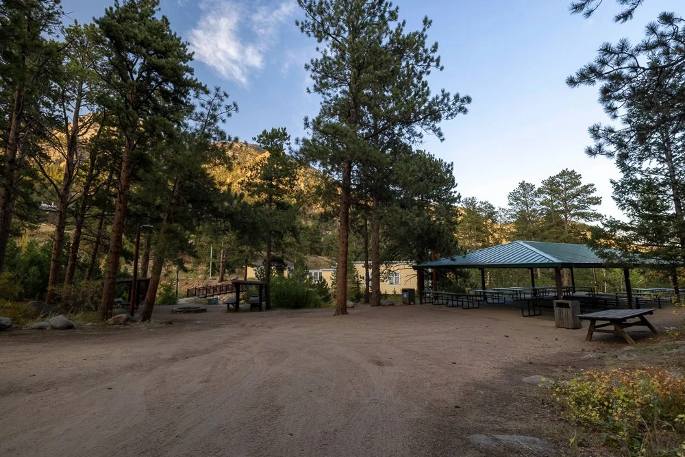 The view from the dirt lot outside of O'Connor Pavilion in Estes Park. This site is simply a dirt lot with a covered pavilion, some trees, a trash can, and picnic table.