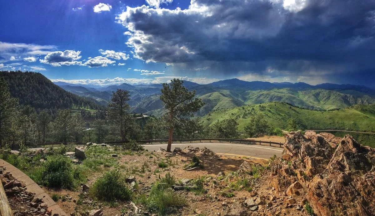 A high up view from Lookout Mountain where you can see the road that curves around the mountain and the lush green foothills in the distance.