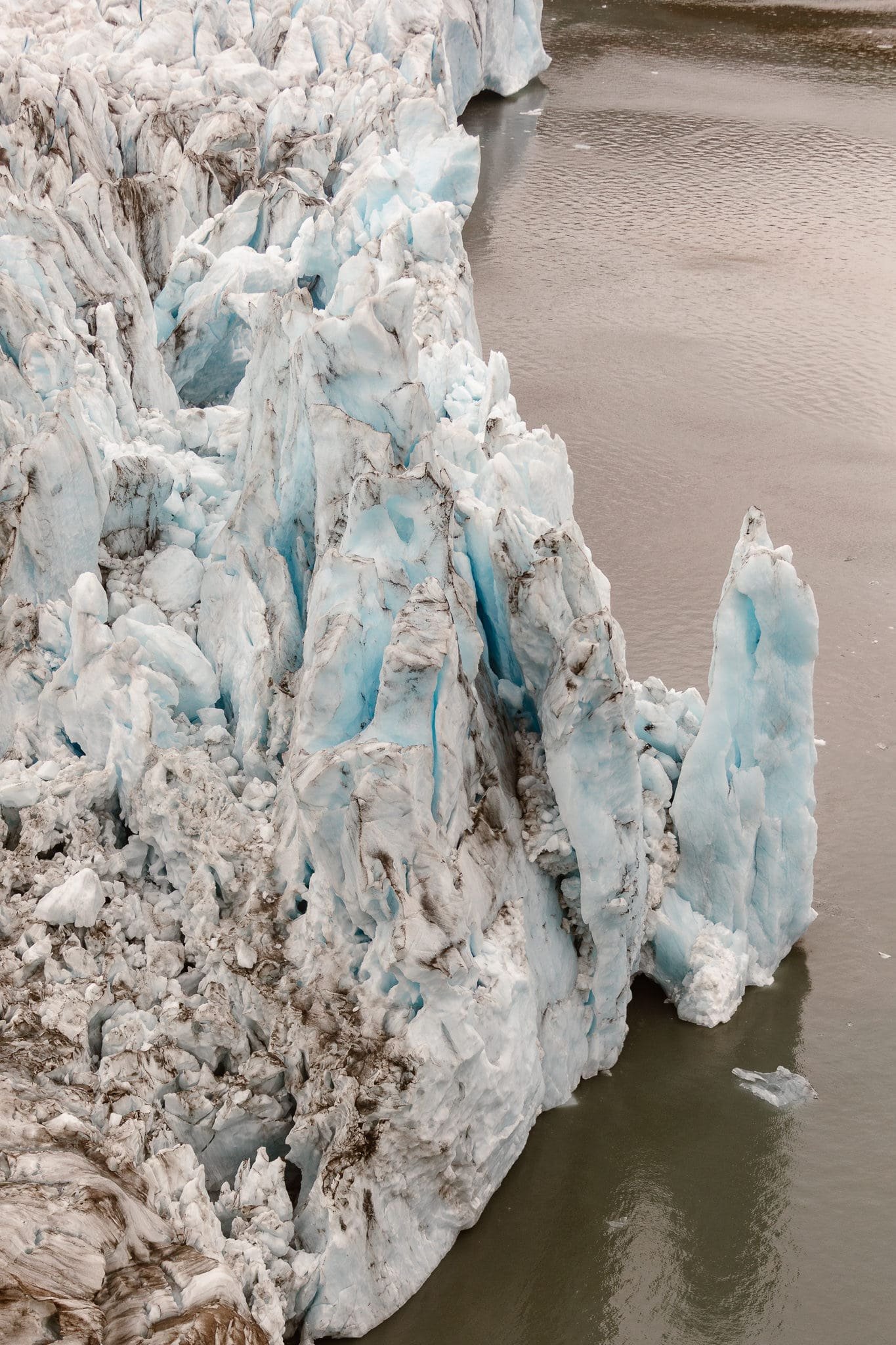 A section of a gigantic light blue iceberg the couple flew by during their helicopter ride to Bear Glacier. The iceberg is vast and rich with jagged peaks throughout this work of art.