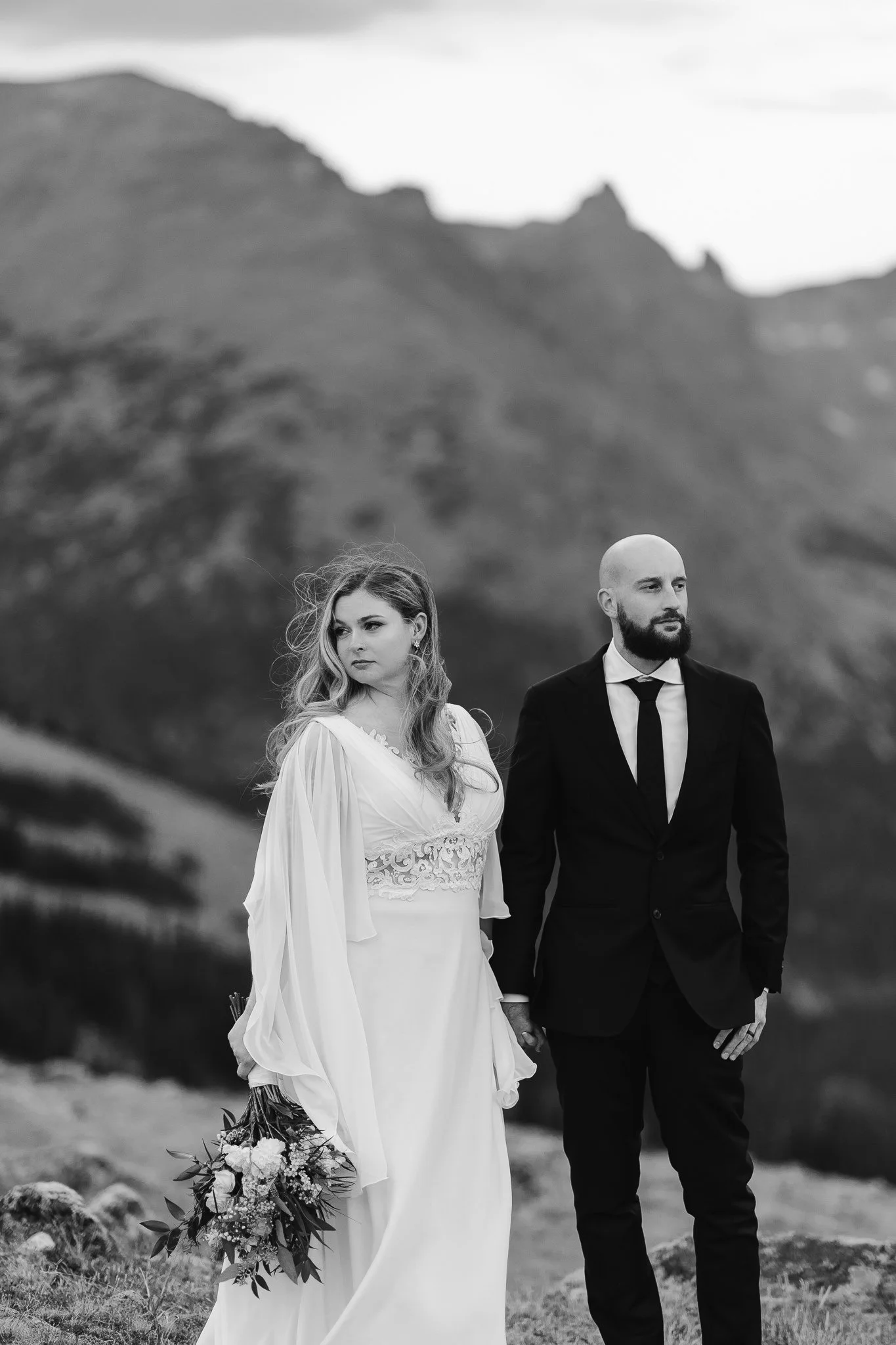 A black and white photo of the bride and groom standing in solidarity and stillness amongst the mountains of Rocky Mountain National Park.