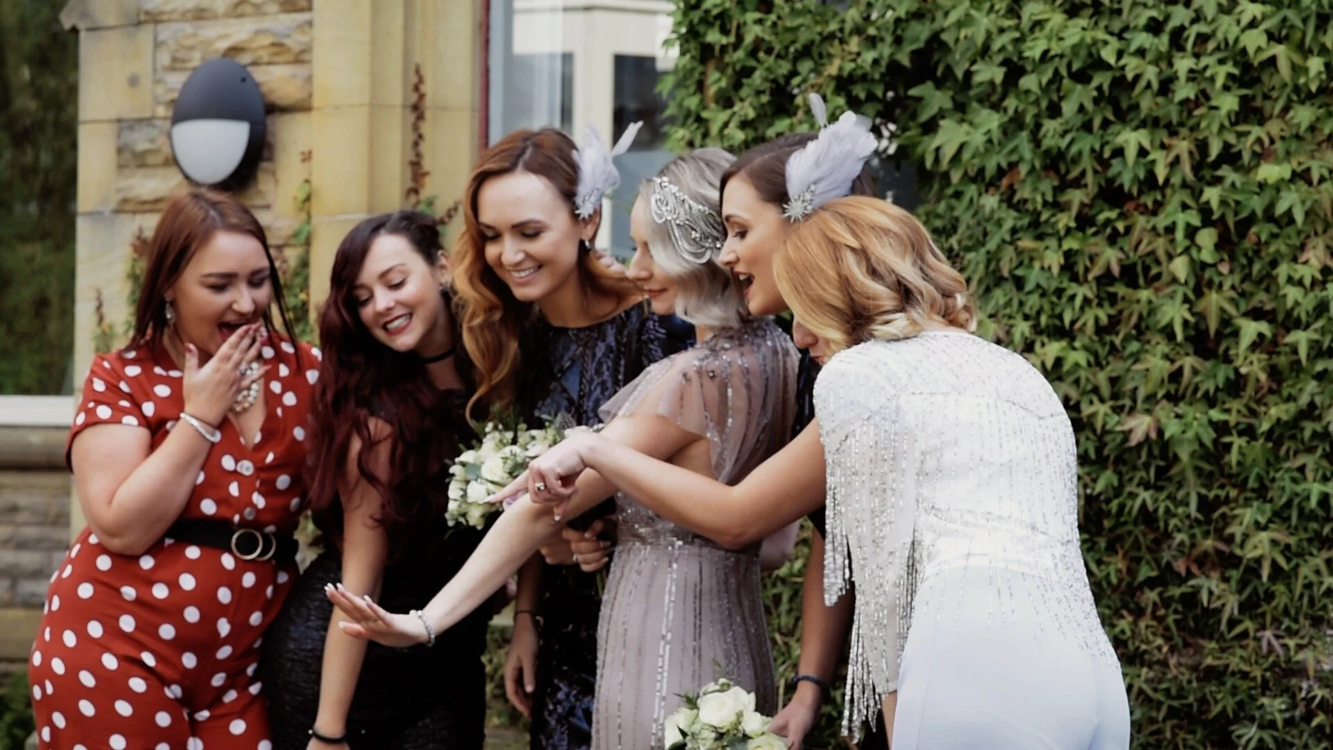The bride having a picture taken with her bridesmaids and friends. They are all looking at her wedding ring and pointing in shock to the fact that she is now officially married.