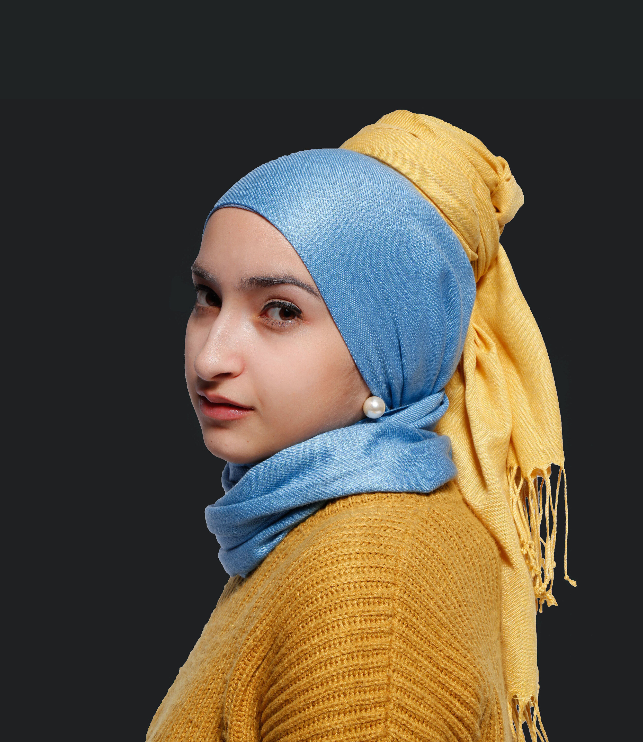 A woman dressed as the girl with a pearl earring painting wearing a hijab.