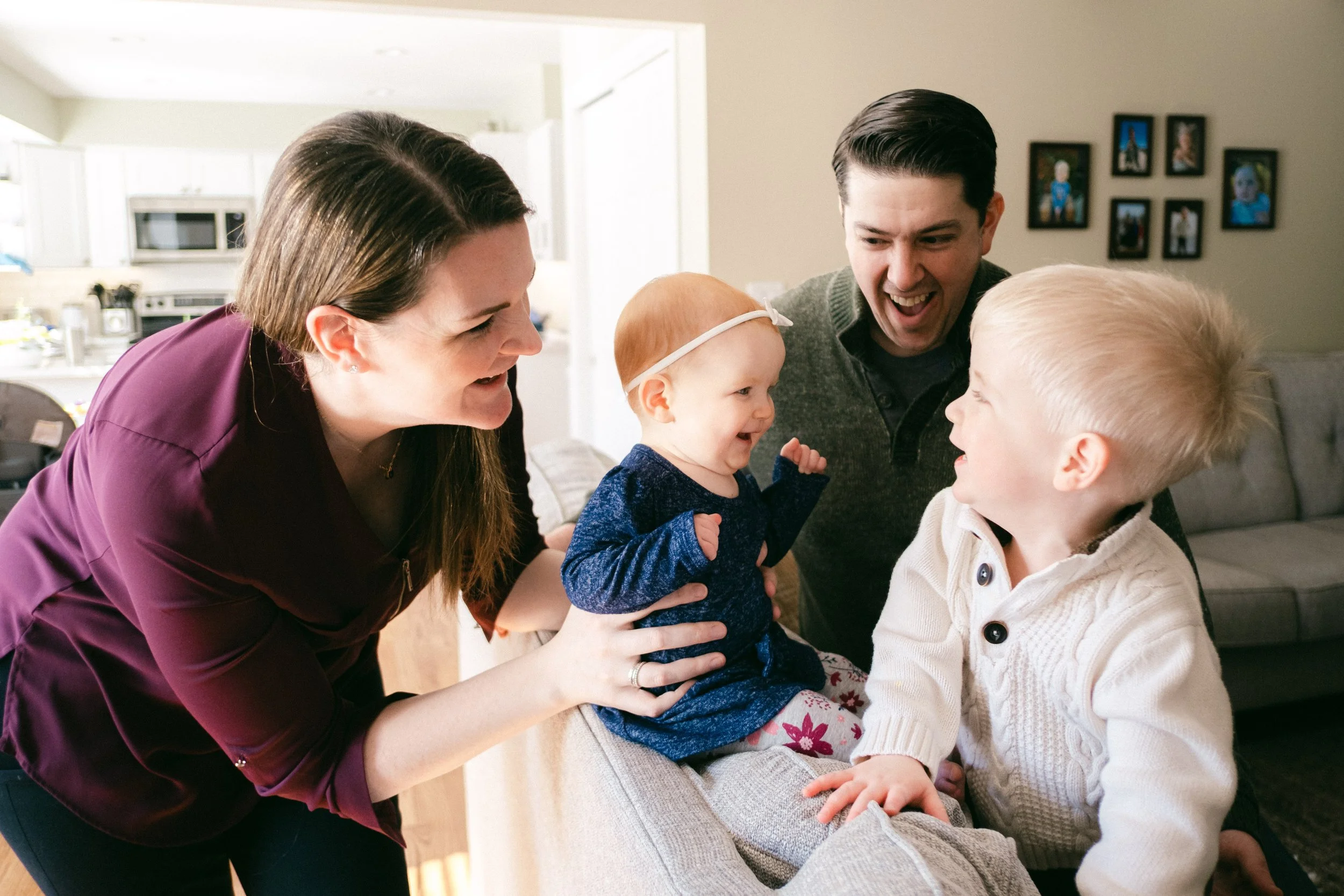 Family with two children smiling and laughing together in a living room.