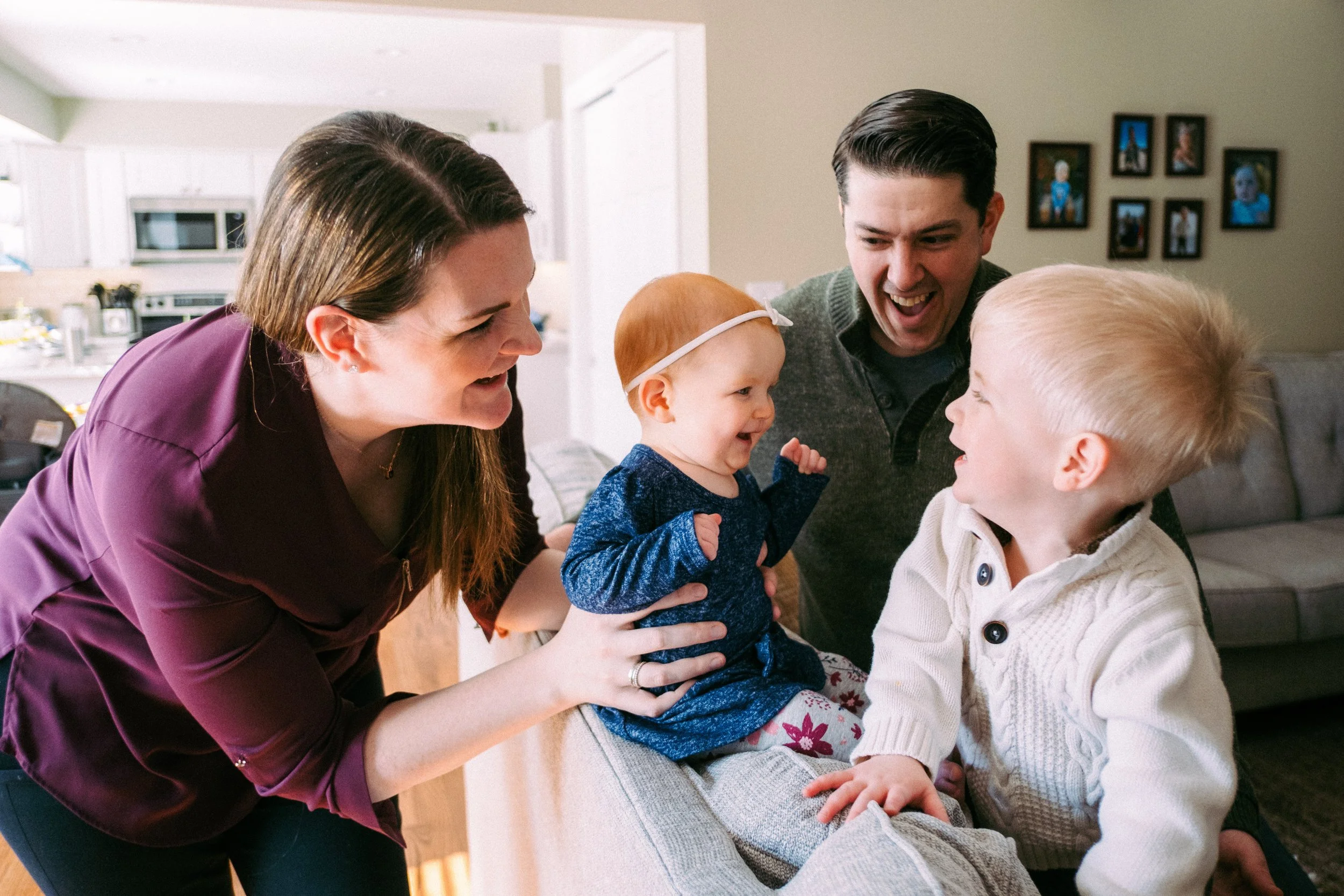 Family with two children smiling and laughing together in a living room.