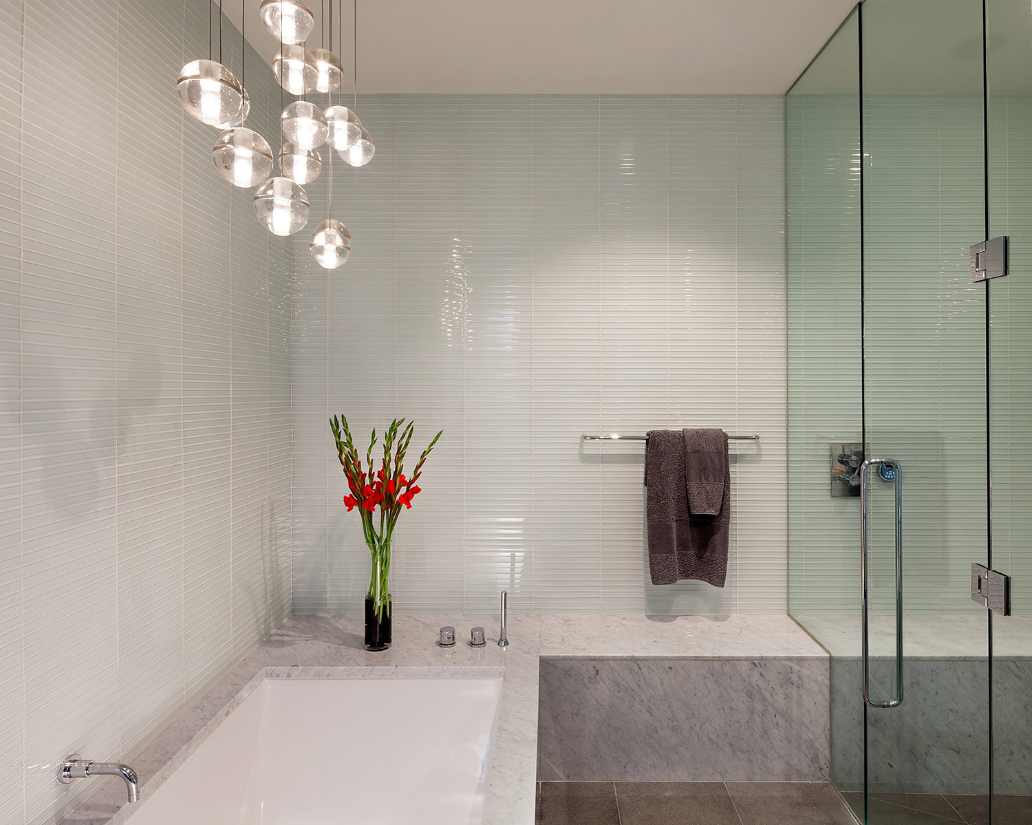 Light gray marble and pale green tile echo the dominant gray and green exterior appearance of the house, and are subtle reference to the presence of nature that surrounds it.