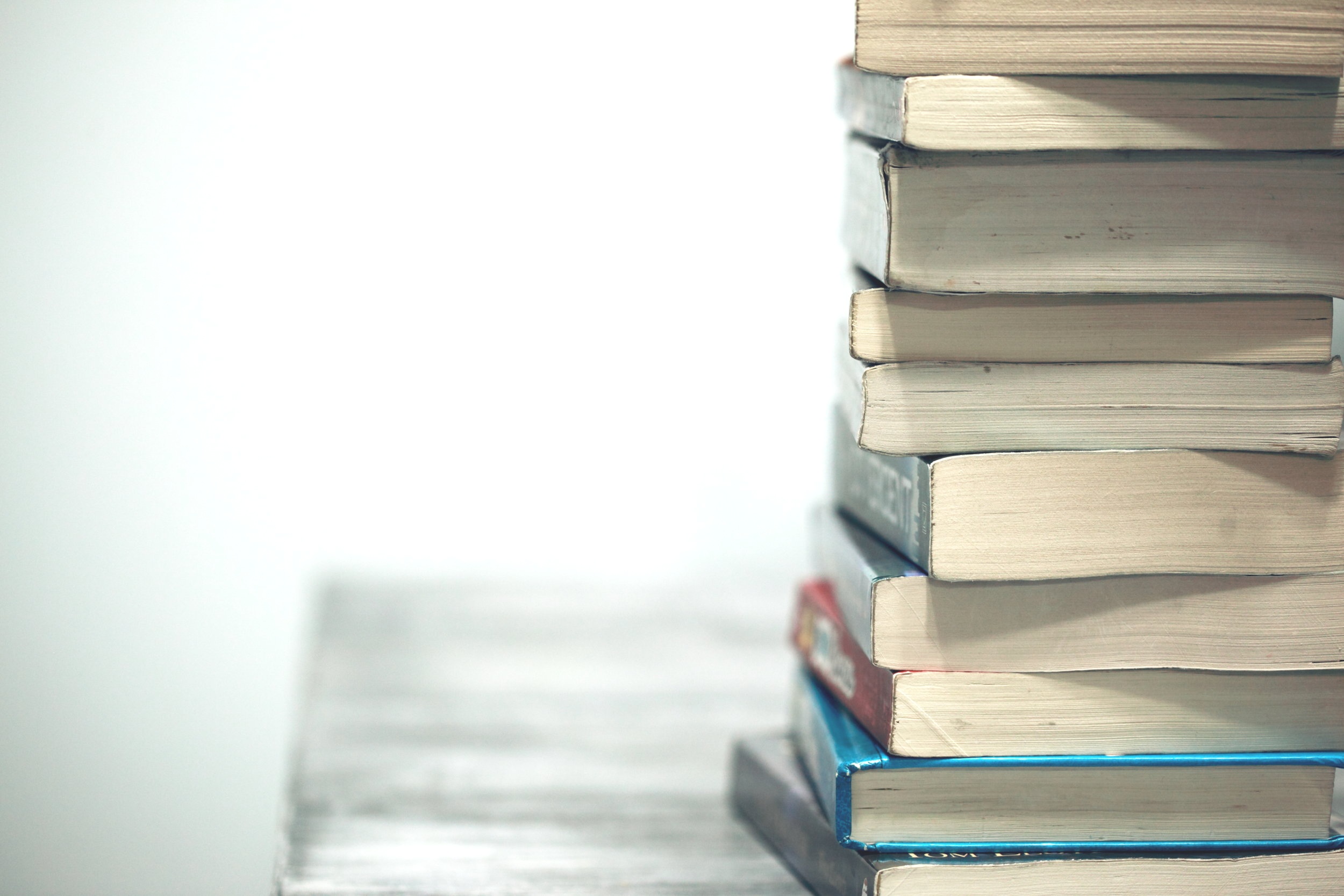 stack of books sitting on a rustic wooden table