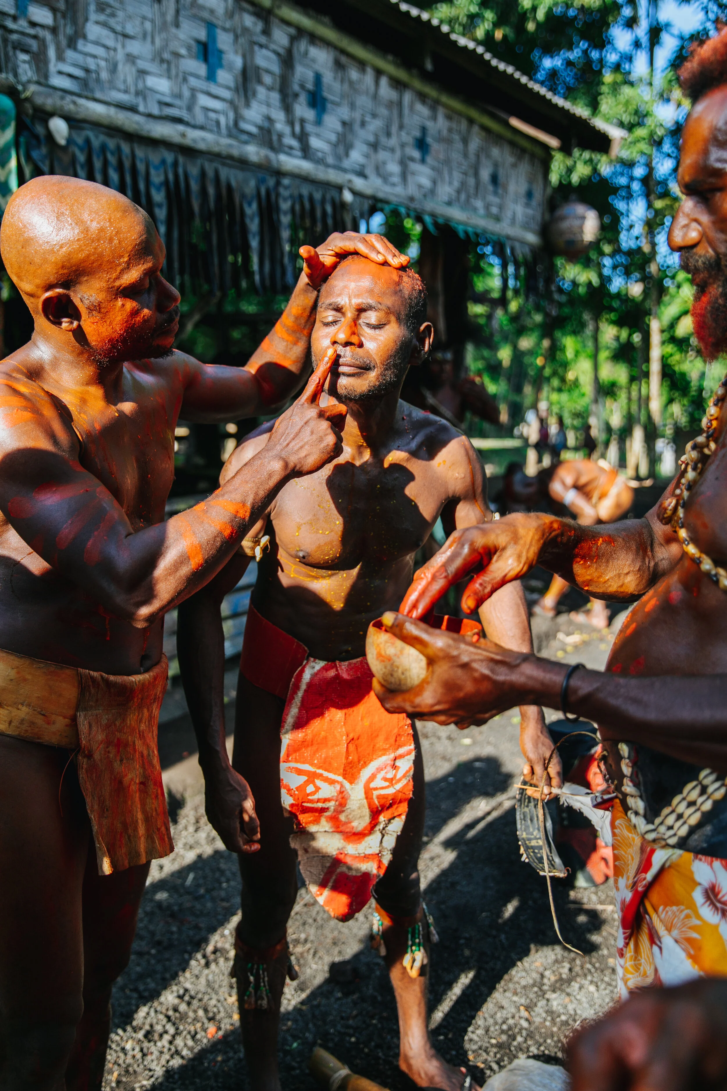 Manam men take turns applying paint behind the village parliament building