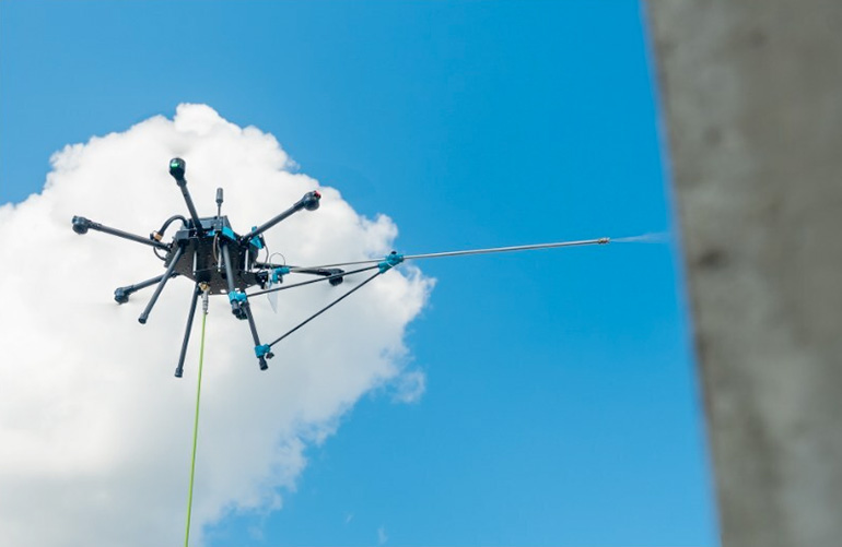 Tethered drone spray washing a building façade