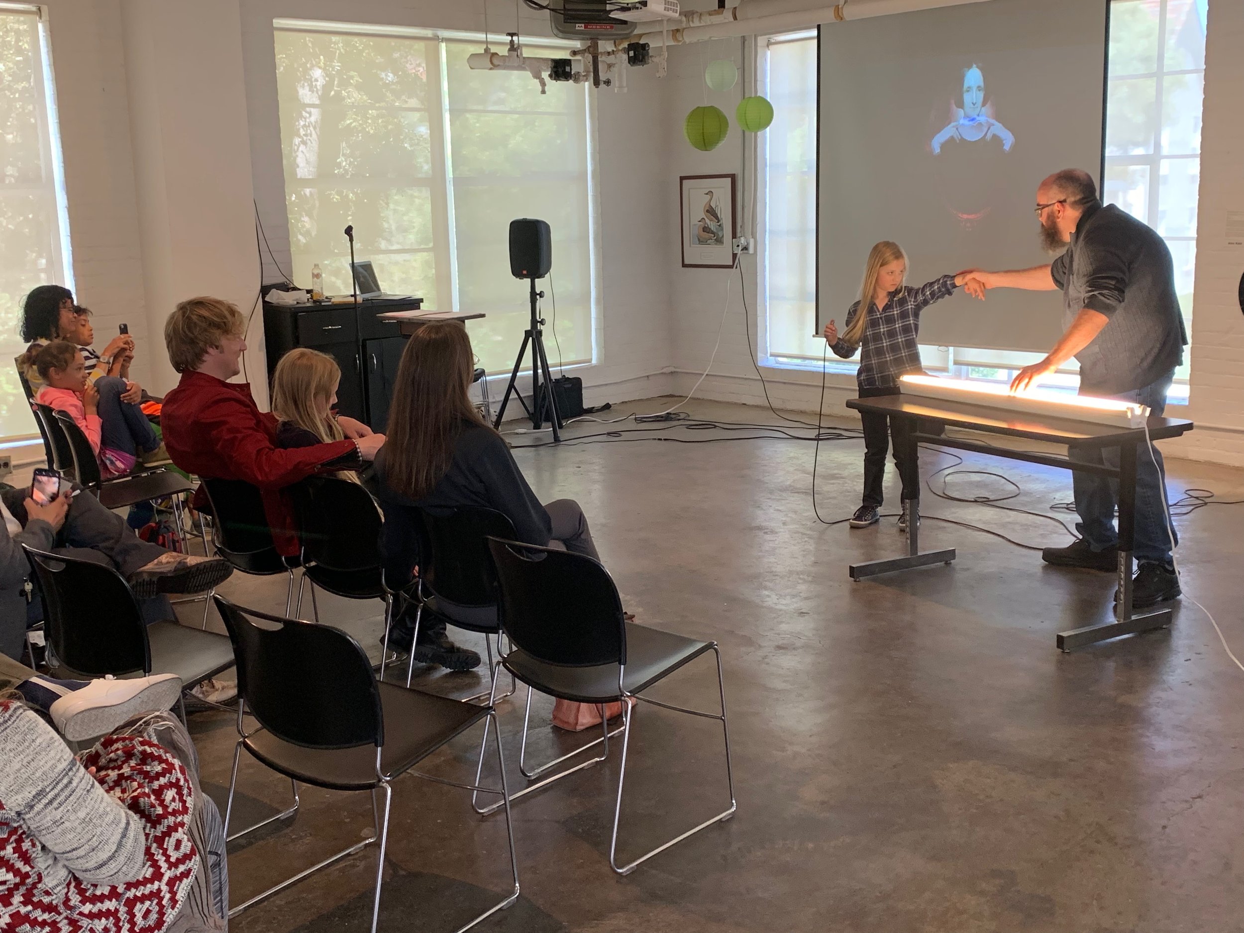  Artist Matthew Weedman and an audience member demonstrate how to turn a light bulb into a musical instrument at Weedman’s performance “It’s Alive!” in the Grabhorn Institute gallery, Summer 2019. 