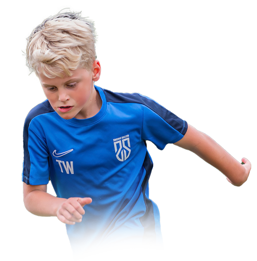 A young boy in a blue soccer jersey running.