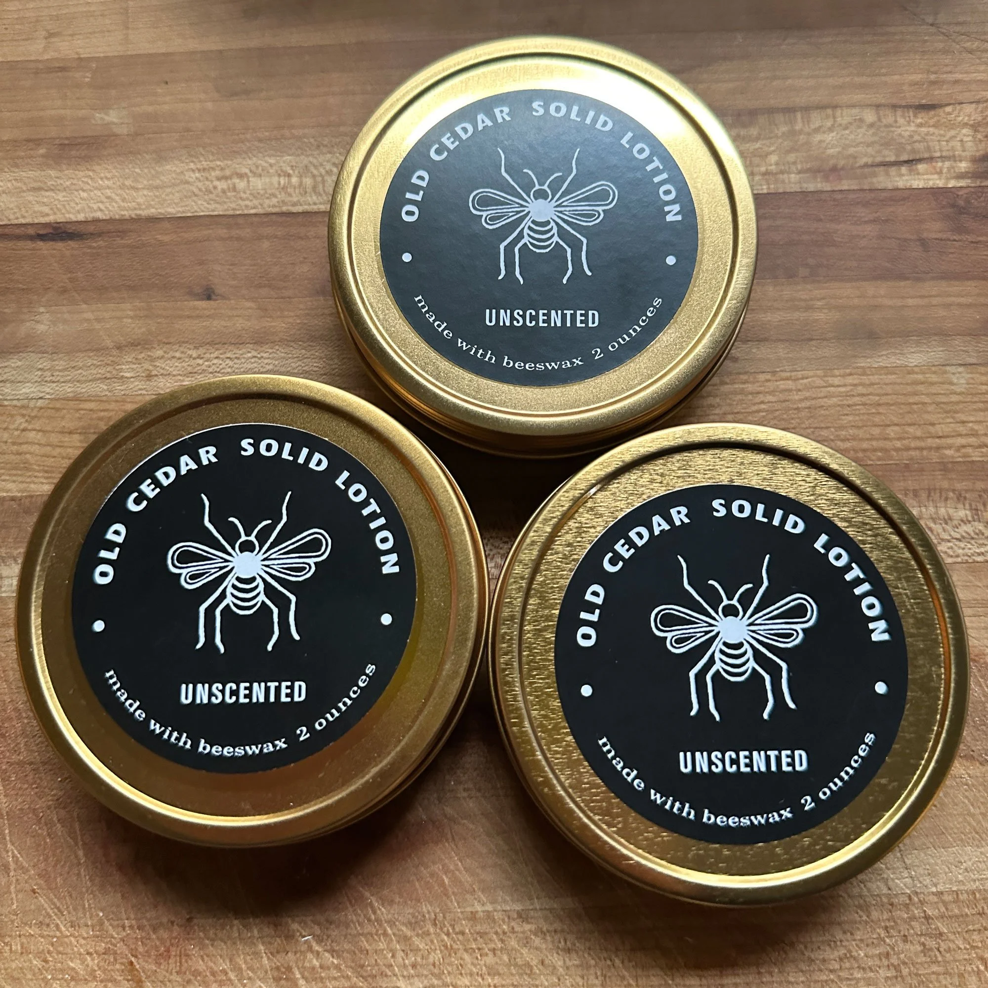 solid beeswax lotion in a metal tin, black label with white honeybee logo and typography