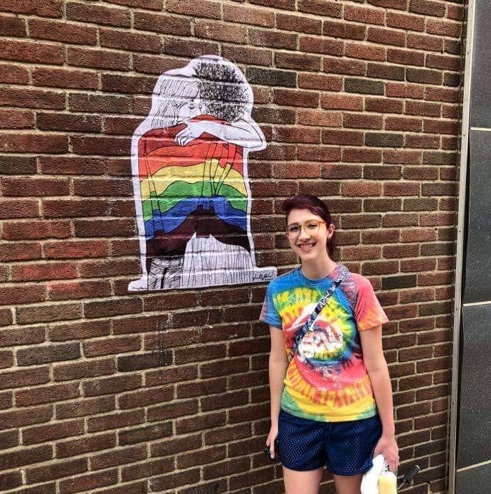 Sam with their wheatpaste mural, "Acceptance"