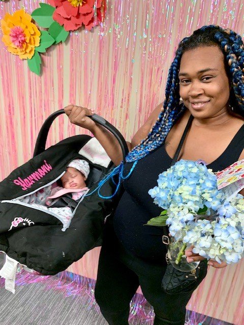pic of mom with baby in carrier and flowers.jpg