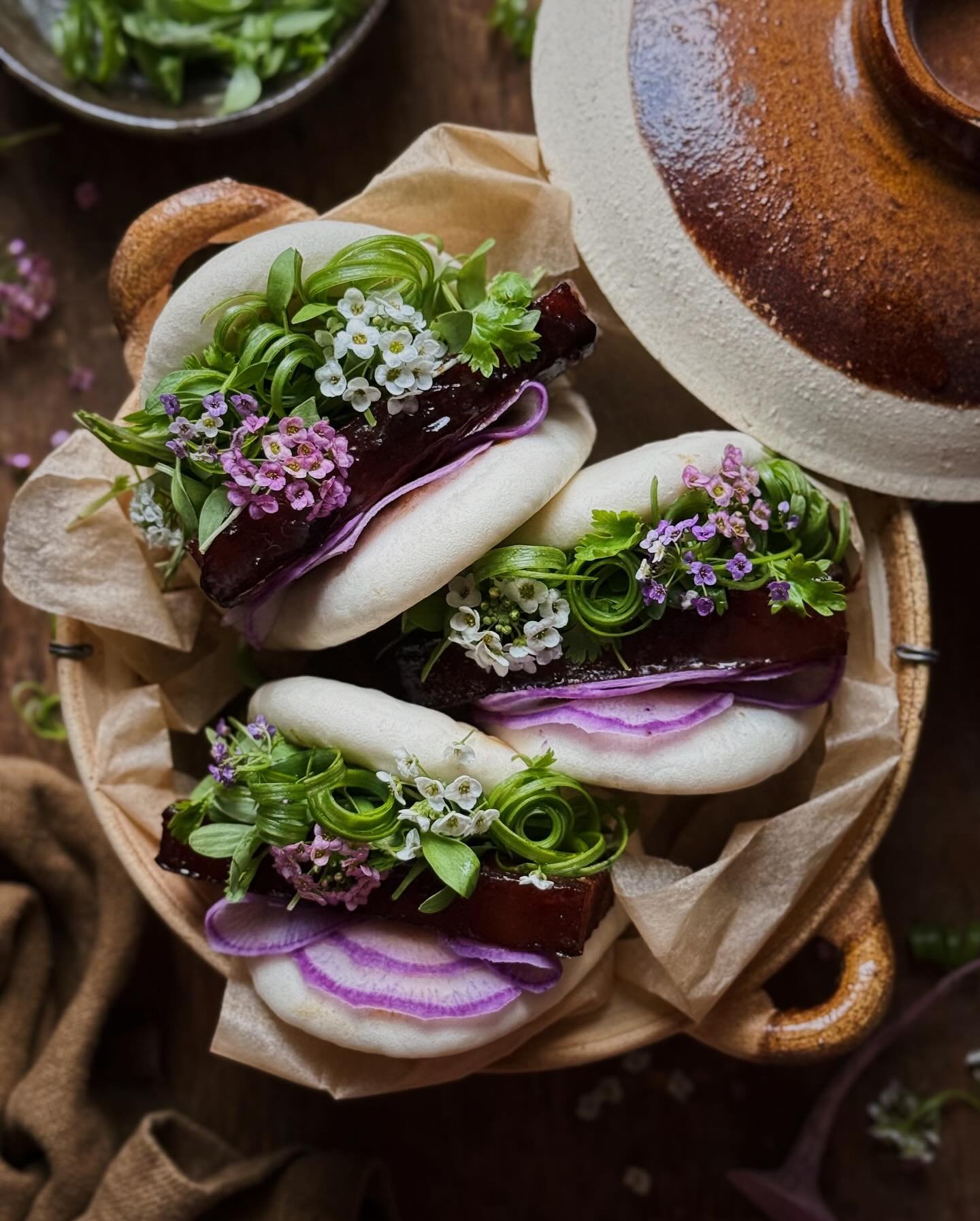 Braised pork belly bao&mdash;thick slices of pork belly slow cooked to tenderness in a char siu inspired aromatic braise and stuffed into fluffy steamed buns along with scallions, micro cilantro, shaved purple daikon, and sweet alyssum flowers.⁣
⁣
I 