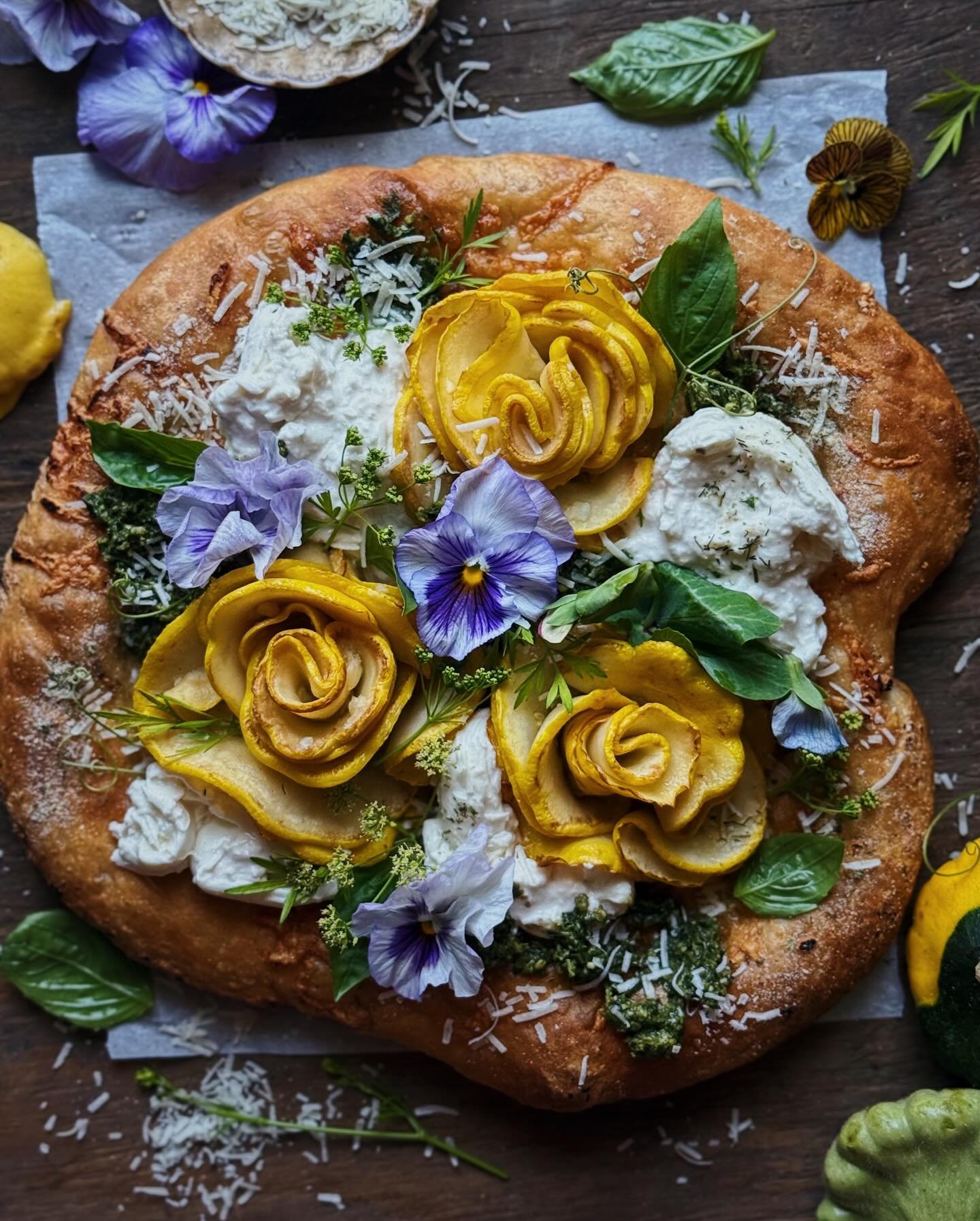 Summer squash focaccia-style flatbread/pizza featuring rosettes made of patty pan squash marinated in lemon and garlic, homemade basil + walnut pesto, toum (Lebanese garlic sauce), white cheddar, truffle burrata, parmesan, ranch seasoning, and fresh 