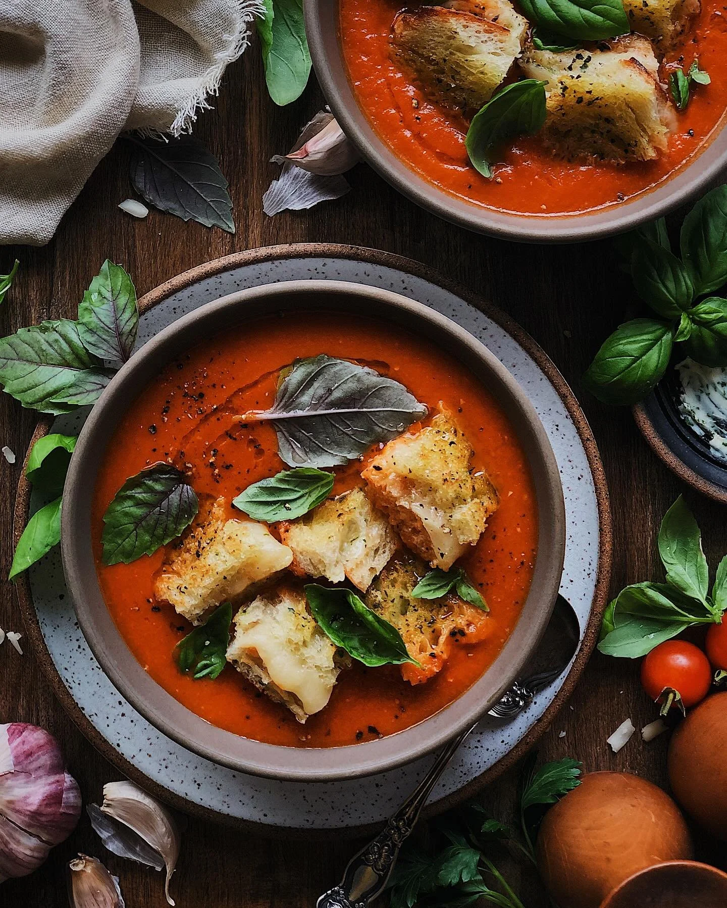 My easy tomato soup topped with cracked pepper, olive oil, fresh basil, and grilled cheese croutons made of pan-fried herb-buttered sourdough, melty white cheddar and gruyere,  and sriracha.⁣⁣
⁣⁣
It is just starting to feel like soup season over here