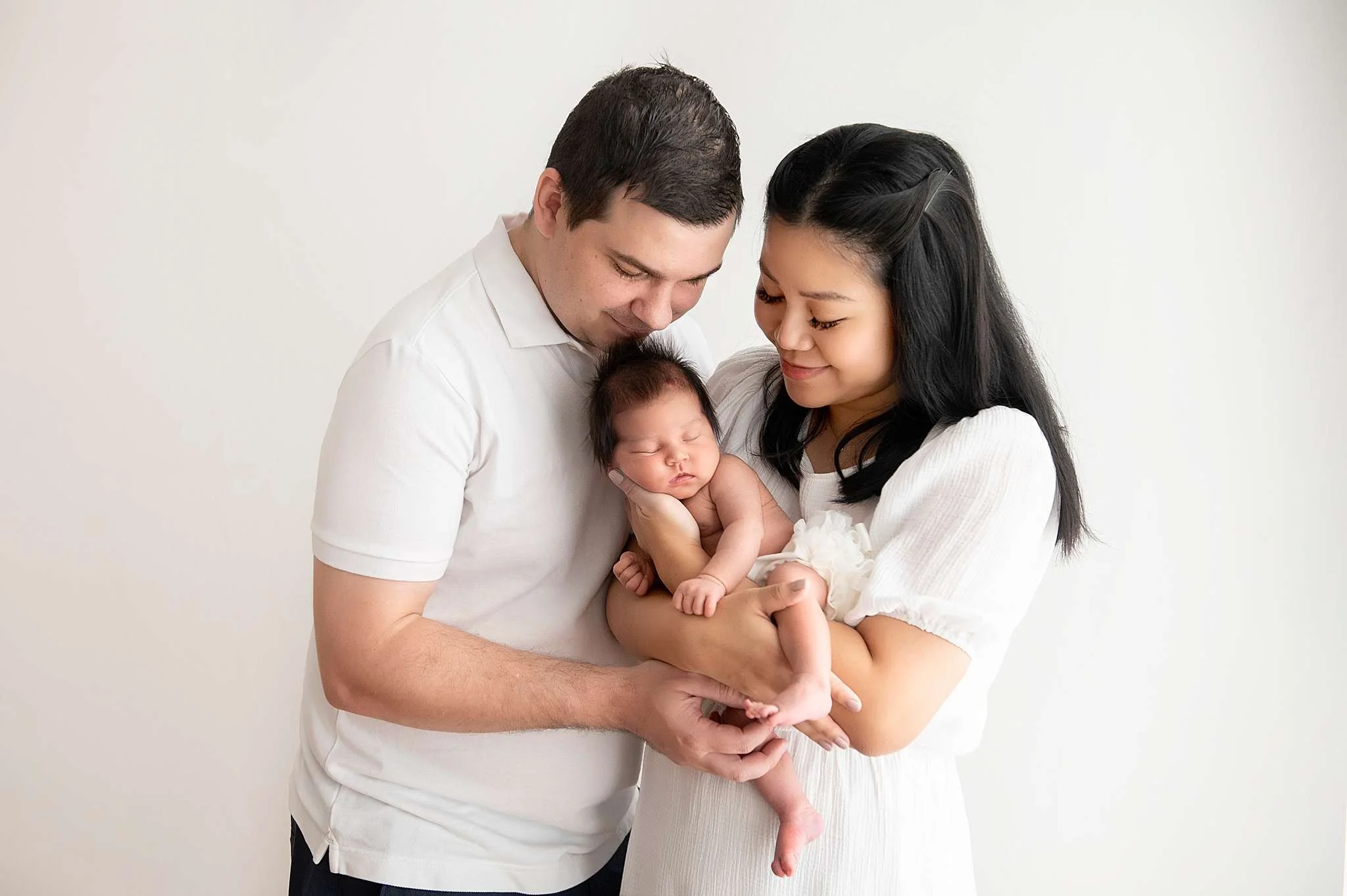 Newborn baby sleeping in his parents' arms during a Sydney newborn studio photography session