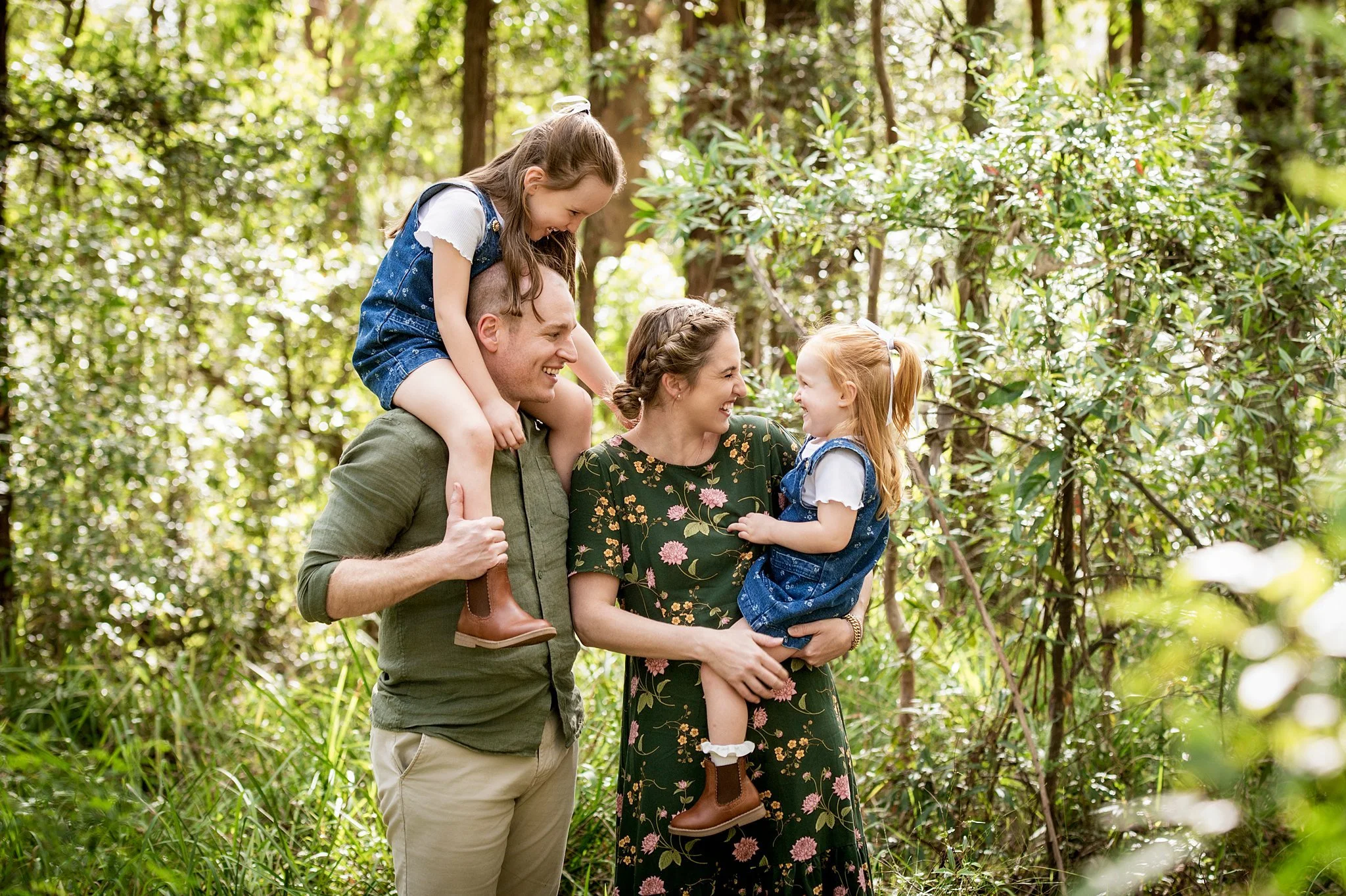 Mum, dad and two daughters laughing together during an outdoor bush family photo session in Sydney's North Shore