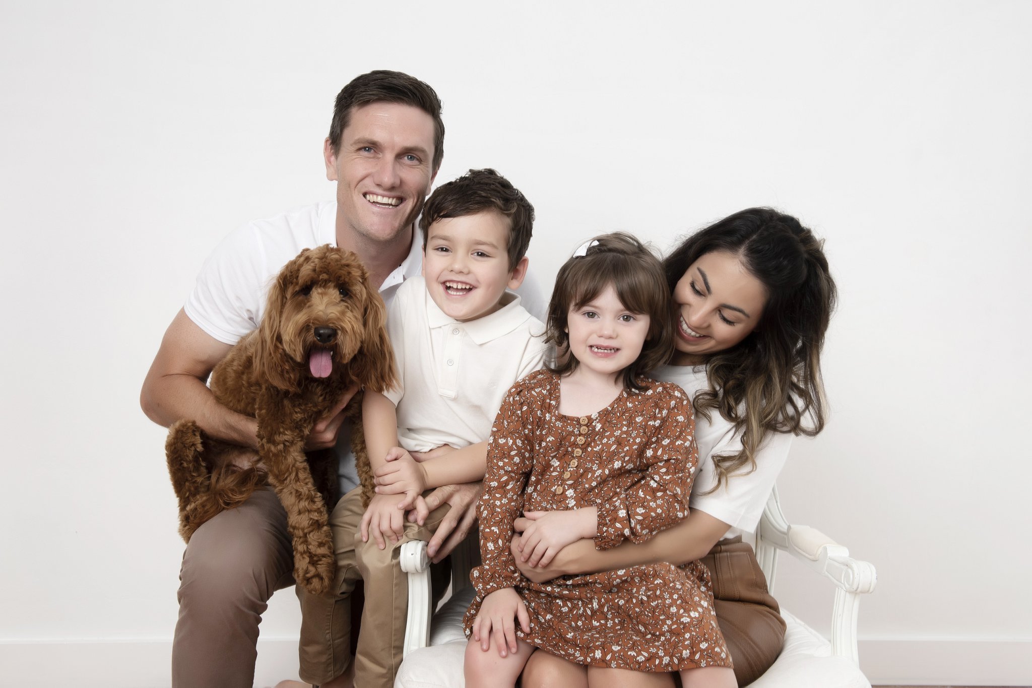 Family of four with a golden labradoodle laughing together during a studio portrait session at über photography, Sydney