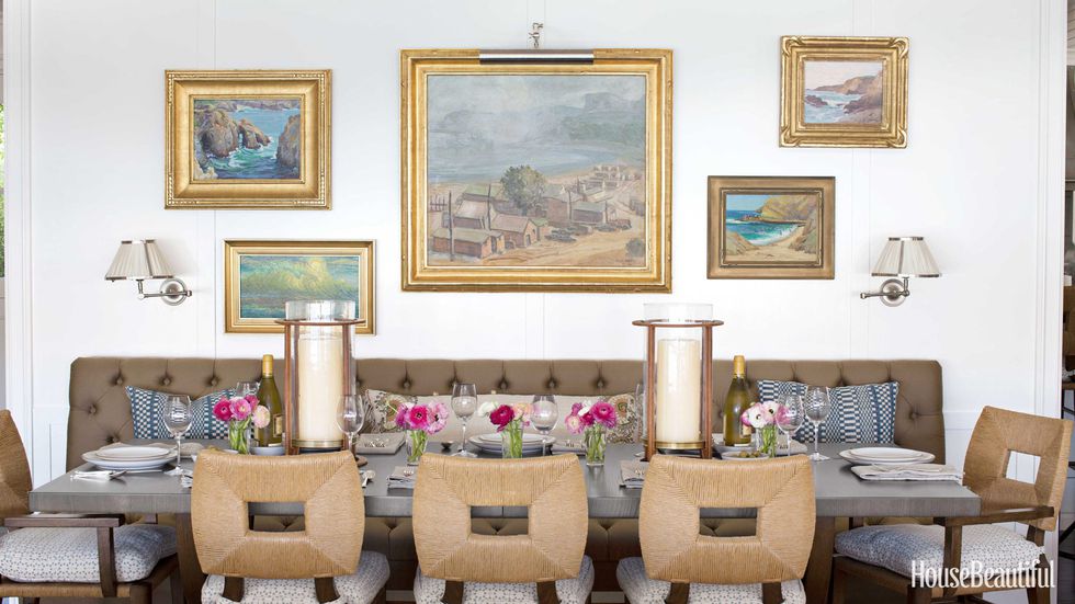 Dining Room   A 10-foot-long banquette makes the dining area one of the most inviting spots in the house. Above it hang California plein-air paintings from the owners' collection. How to Marry a Millionaire rush chairs from  Hollywood at Home . Molador leather hurricanes with brass base from  Mecox .