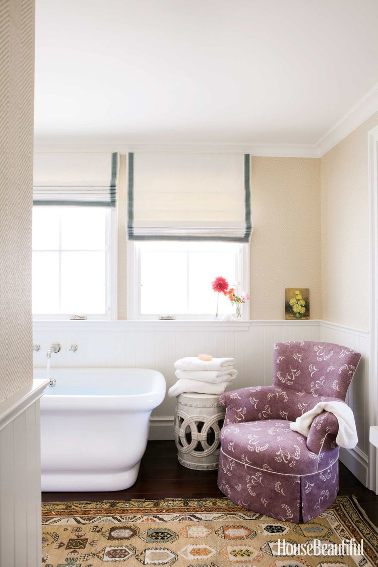 Bathroom   An armchair, a ceramic stool, an aged Persian rug, wallpaper, and Roman shades create a sitting room atmosphere in Susan Croul's bathroom. Dunham's KP Armchair in Carolina Irving Mimosa Vine, from  Hollywood at Home .  Ralph Lauren  herringbone wallpaper.