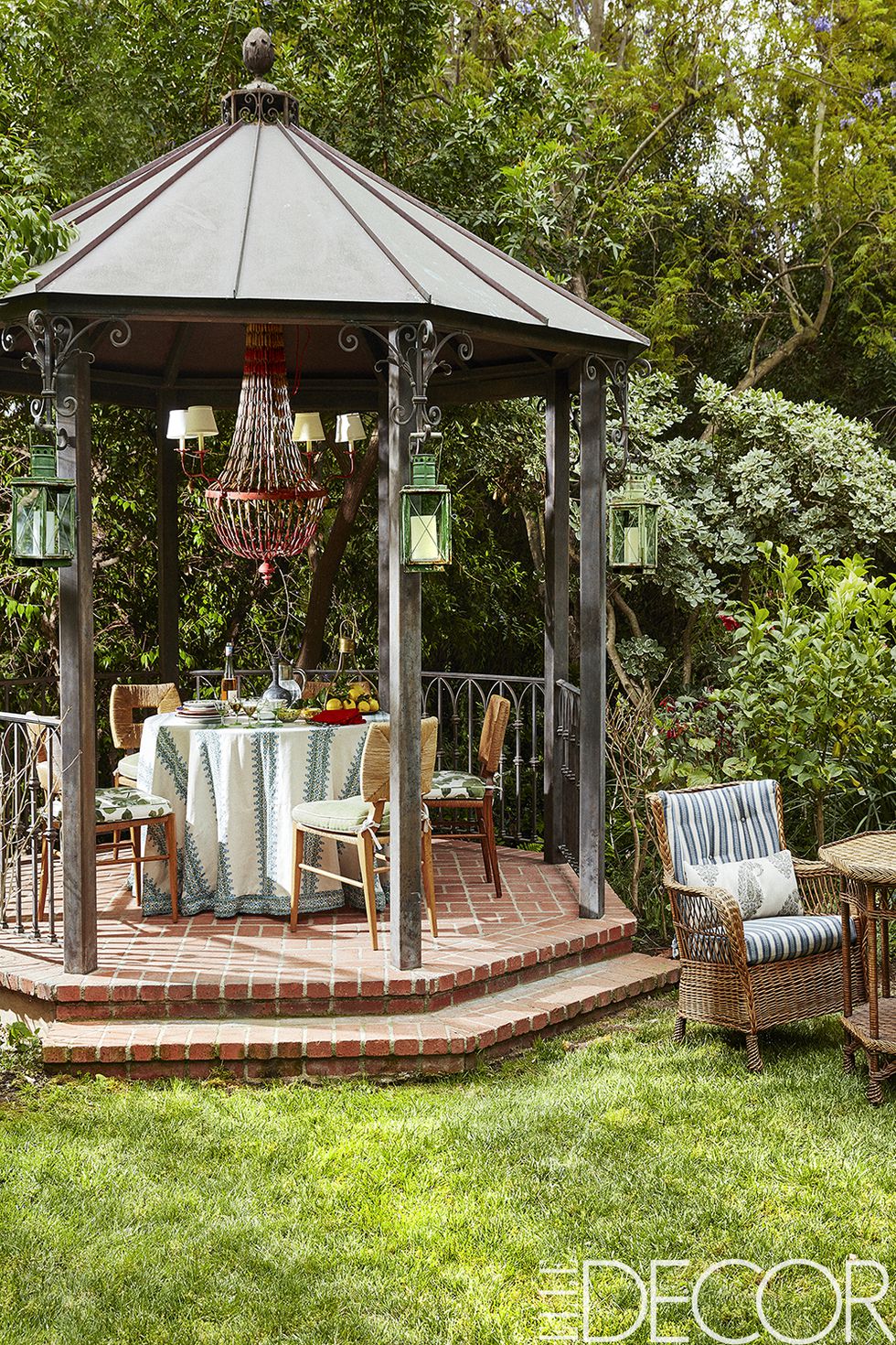 The gazebo’s dining chairs, vintage French chandelier and lanterns are from Hollywood at Home ; the tablecloth and the chair cushions are of fabrics from Peter Dunham Textiles .
